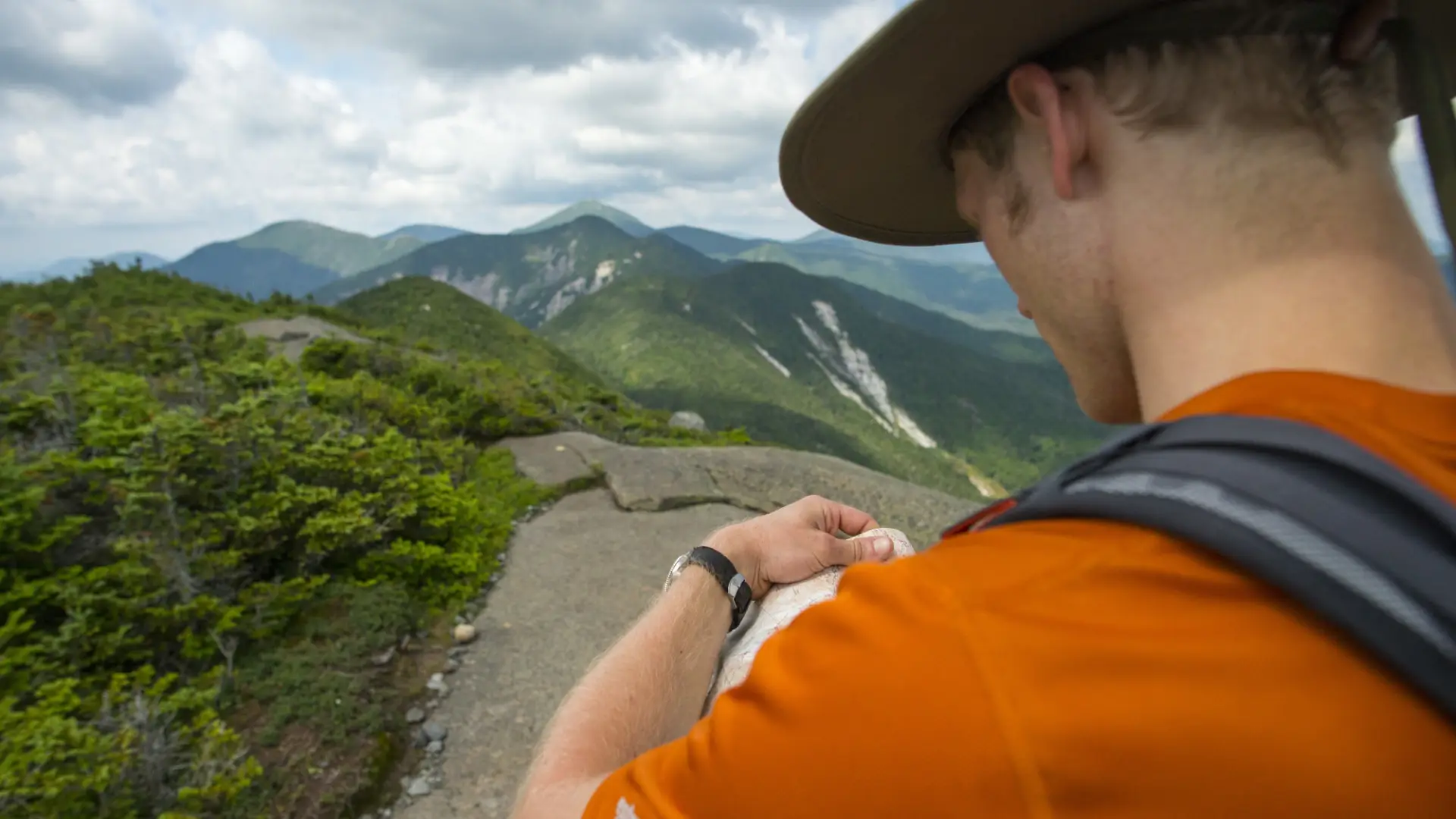 A hiker checks a map on the summit of a mountain