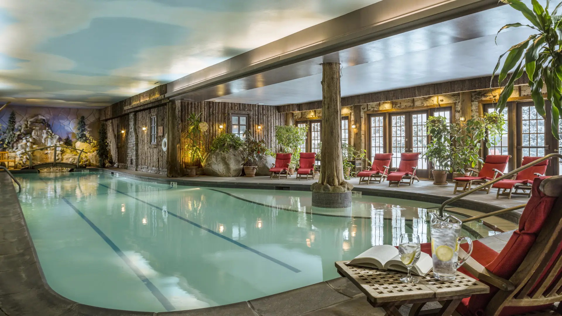 A view of the indoor pool at the Mirror Lake Inn Resort and Spa, with lounge chairs lining the edges of the pool walkway