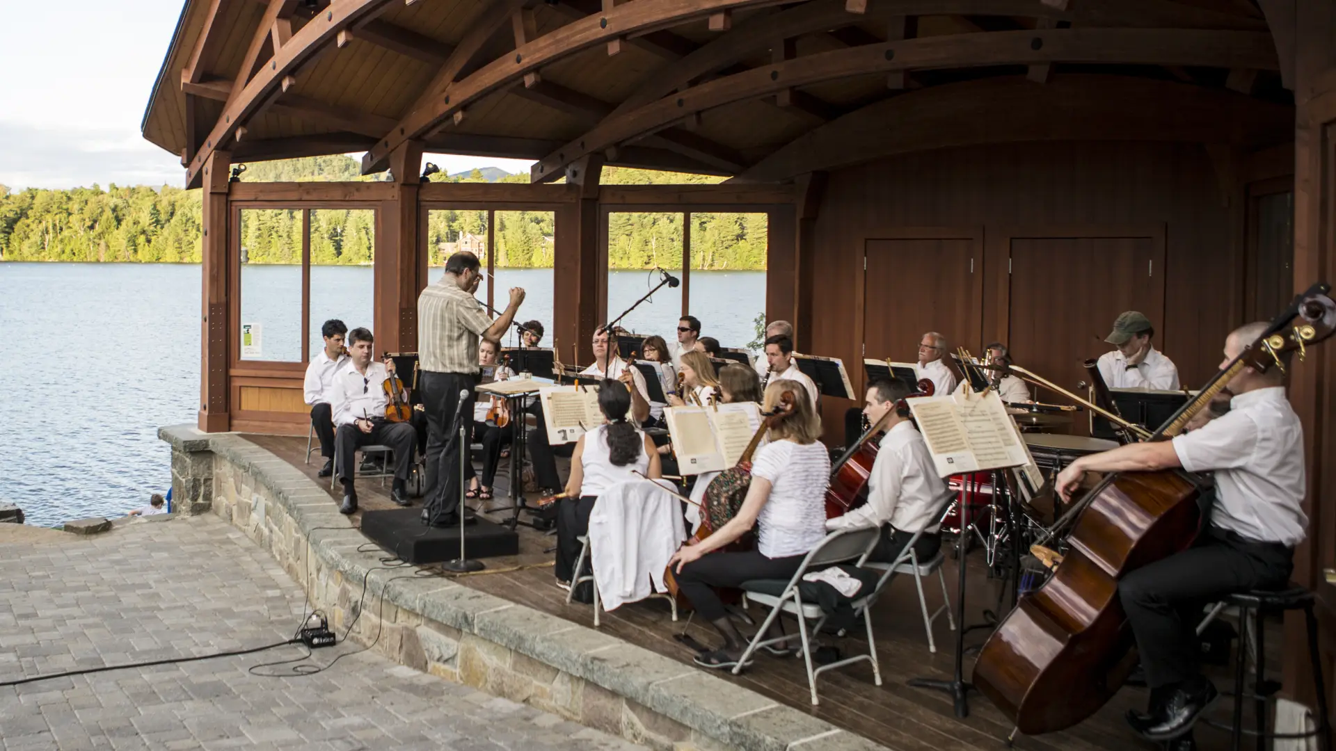 A sinfonietta performs on stage in front of Mirror Lake
