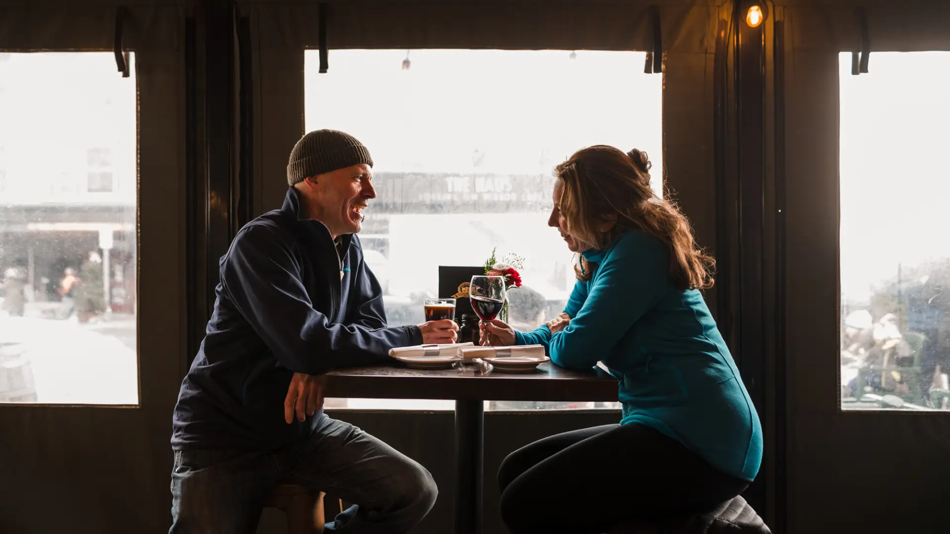 A man and woman enjoy burgers and wine at a restaurant. 