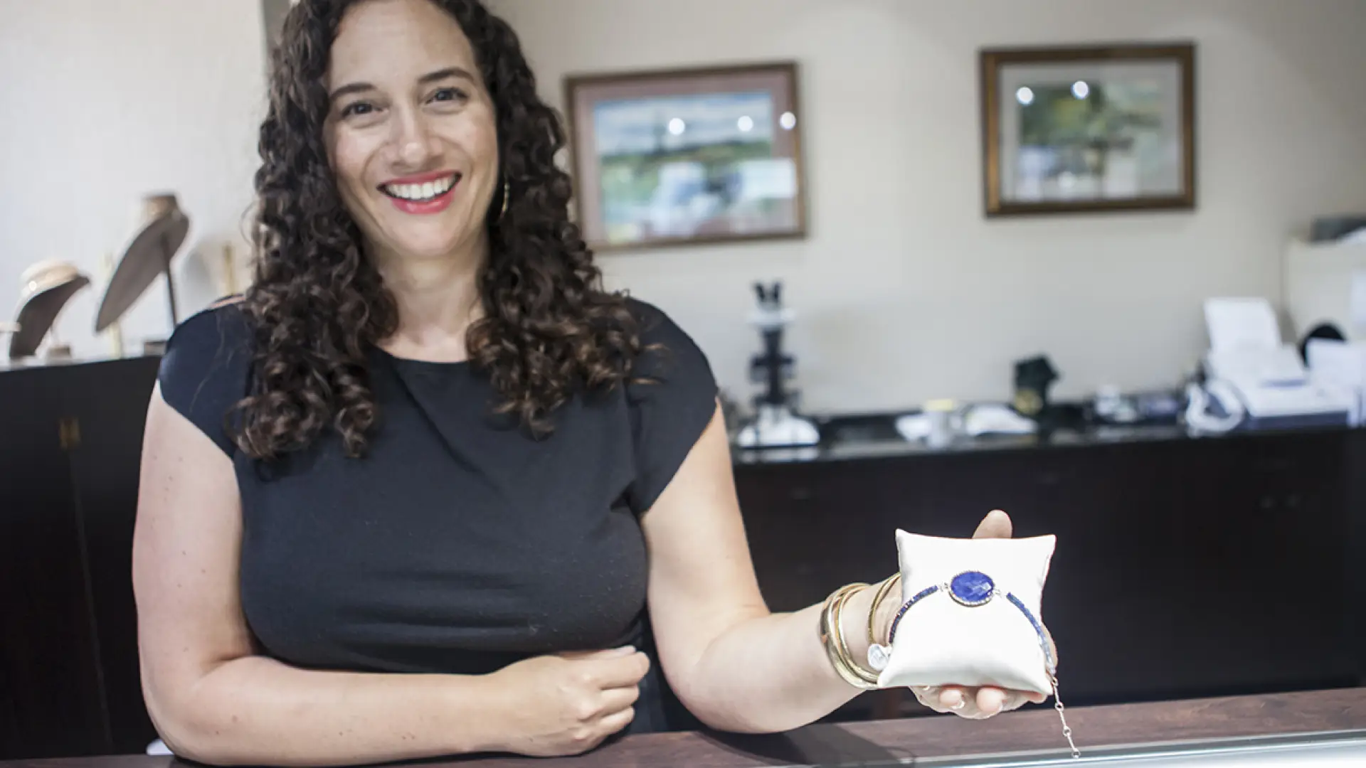 A woman holding up a piece of jewelry in a Lake Placid jewelry store.