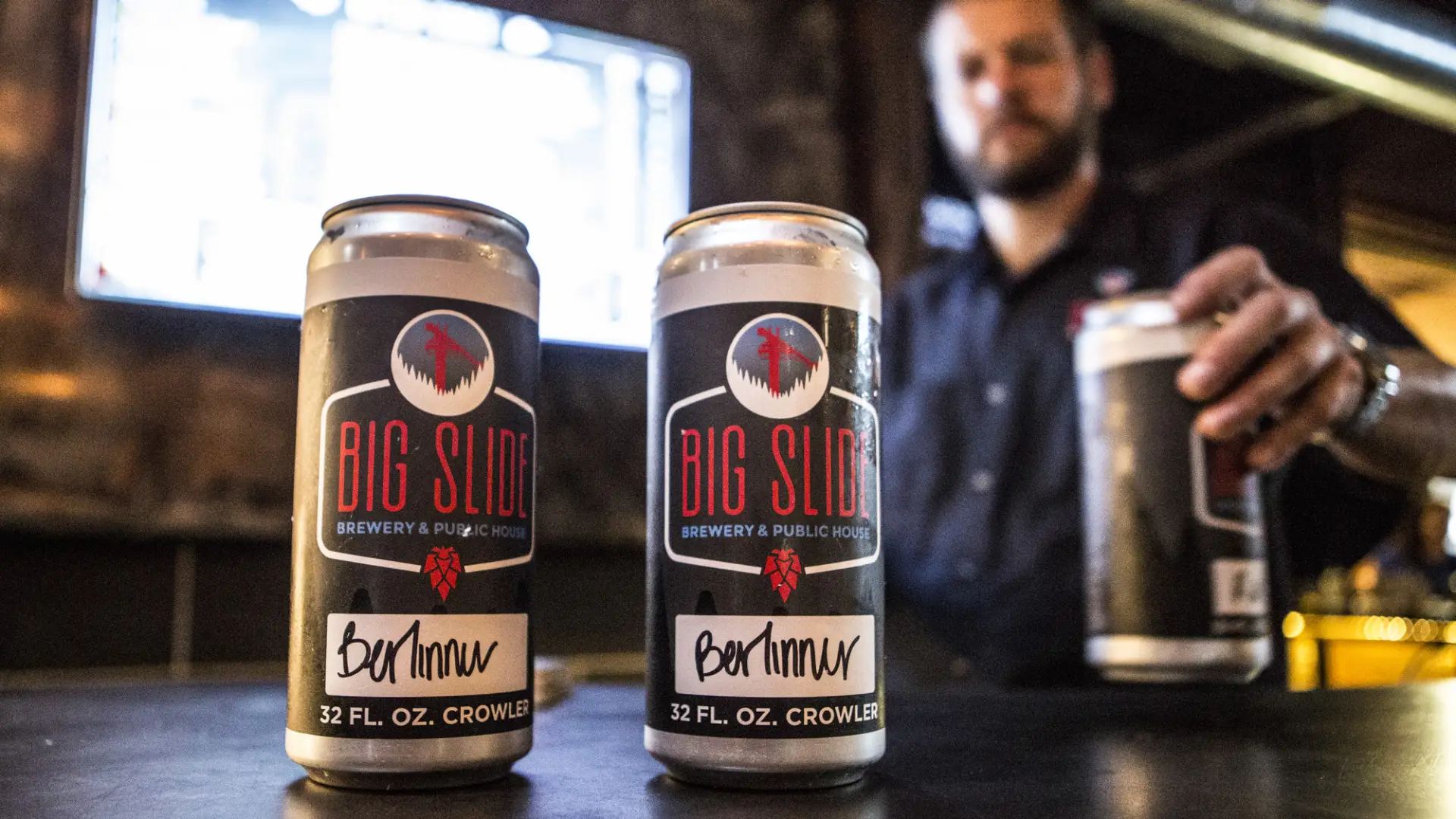 A bartender serves crowlers of beer for patrons to take home.