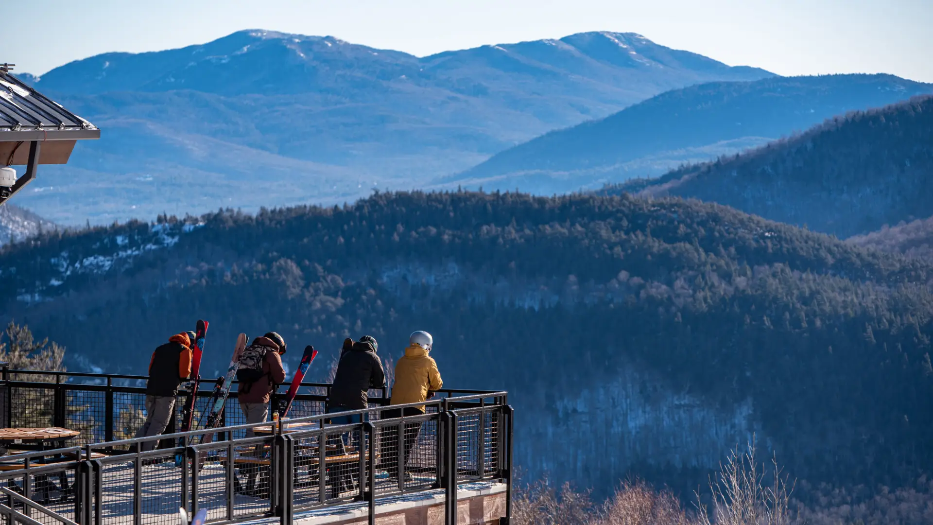 Four friends stand on a patio and look at the winter mountain views across the valley.