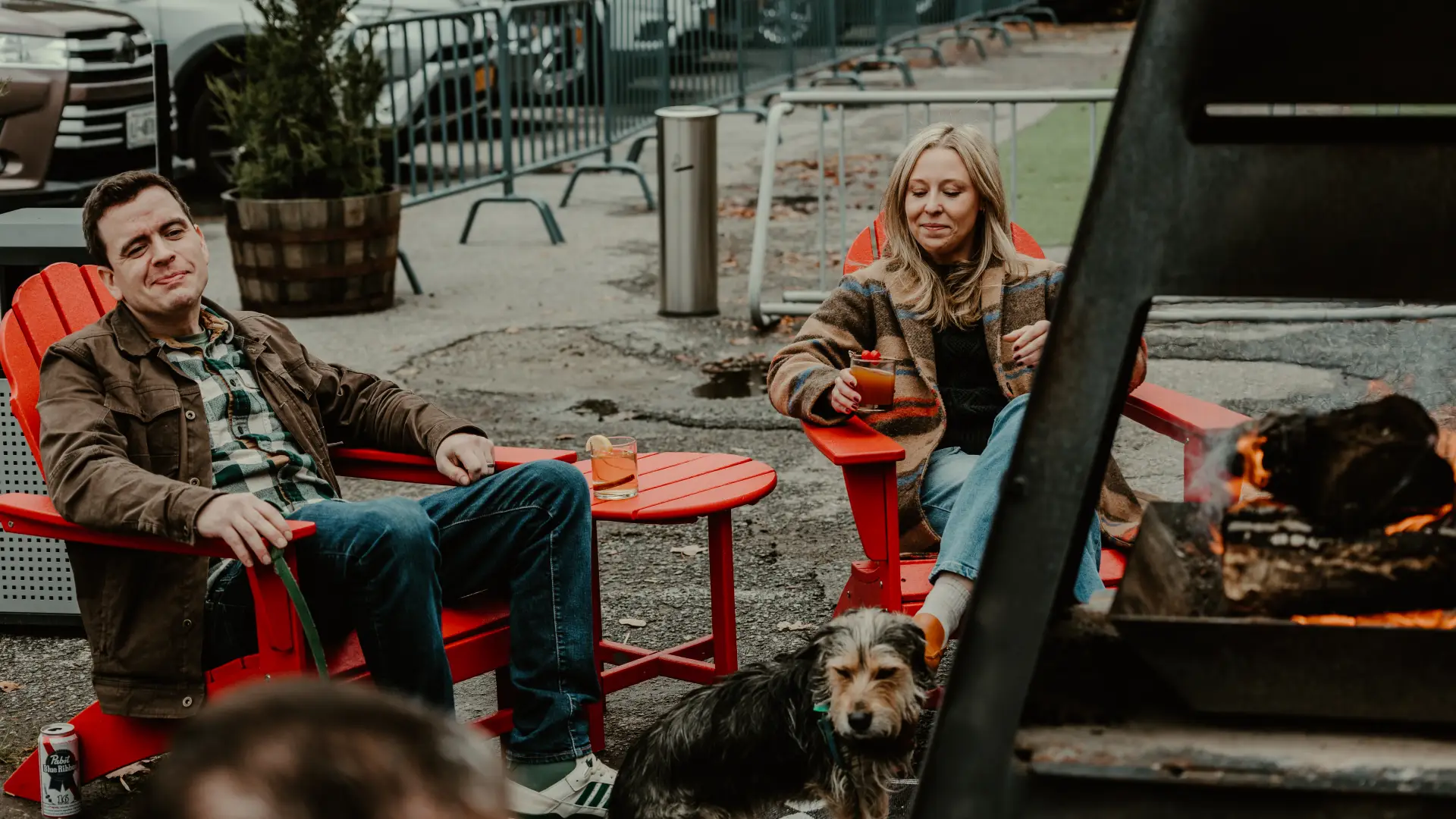 Happy couple enjoys the outdoor space with their pet and some cocktails in red Adirondack chairs.  Photo Credit to A. Kelly.