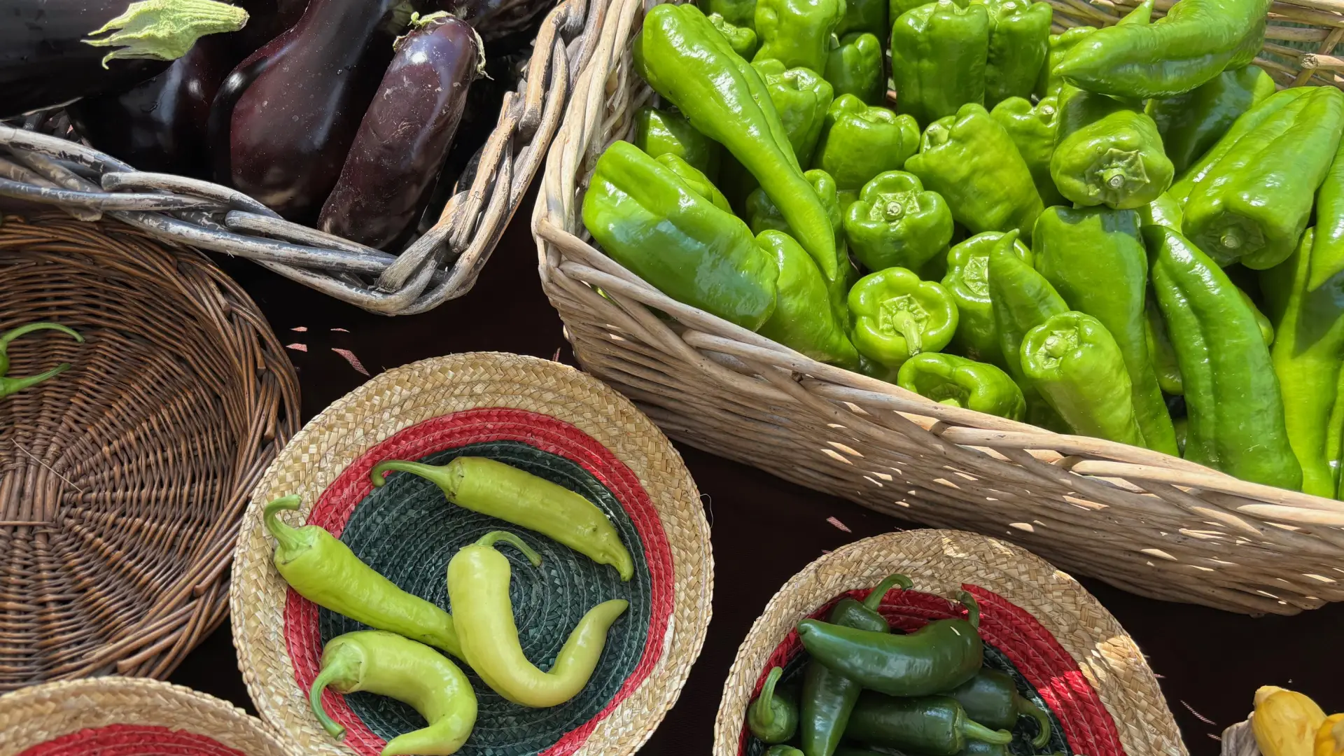 Beautiful peppers and eggplants on display in baskets