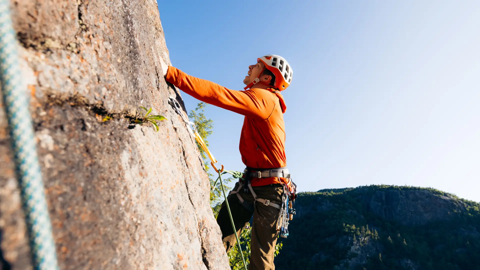 A man climbs a mountain side. 