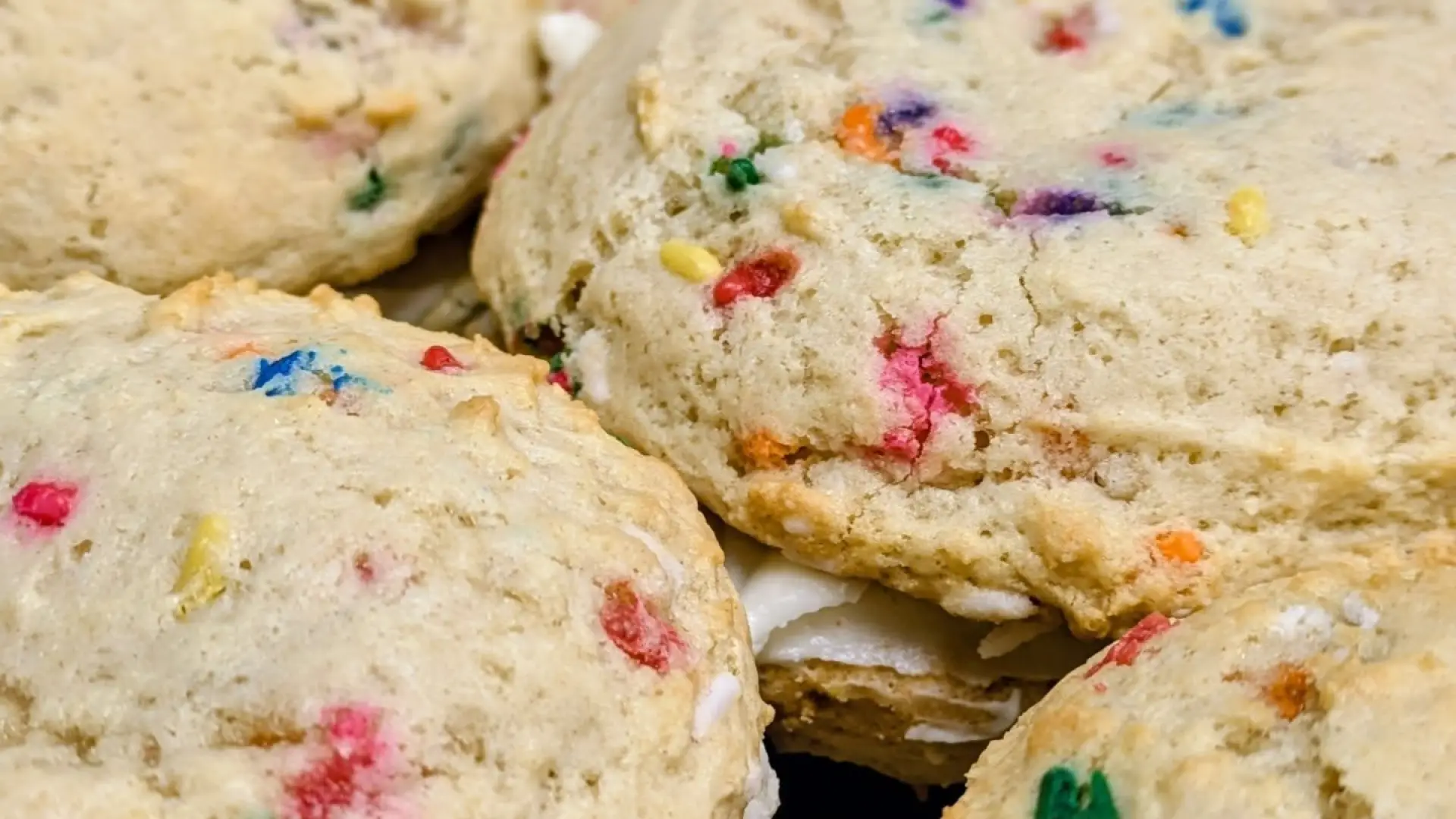 Cookie sandwiches made with rainbow sprinkle cookies and filled with whipped cream.