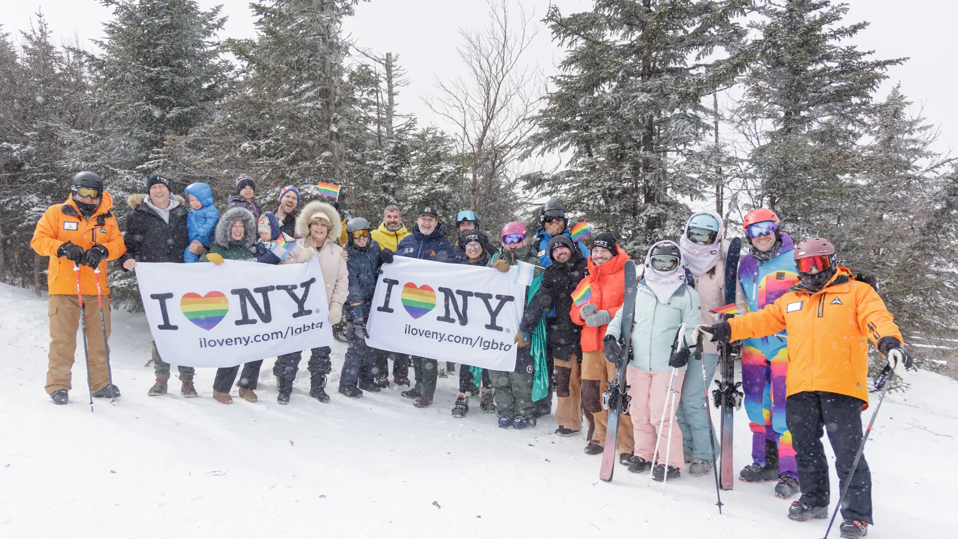 A group of skiers at Whiteface Mountain, holding pride flags and small rainbow flags to celebrate Adirondack Winter Pride.