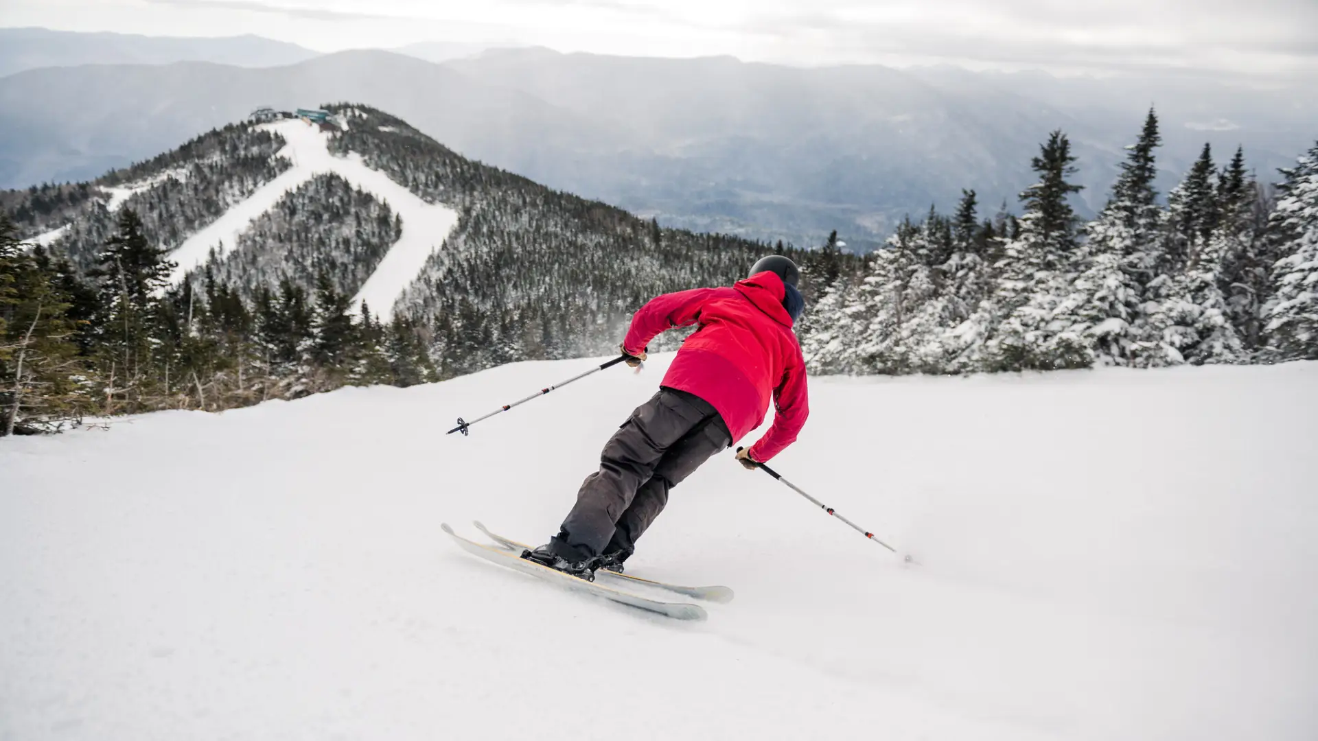 A man in a red jacket goes skiing. 