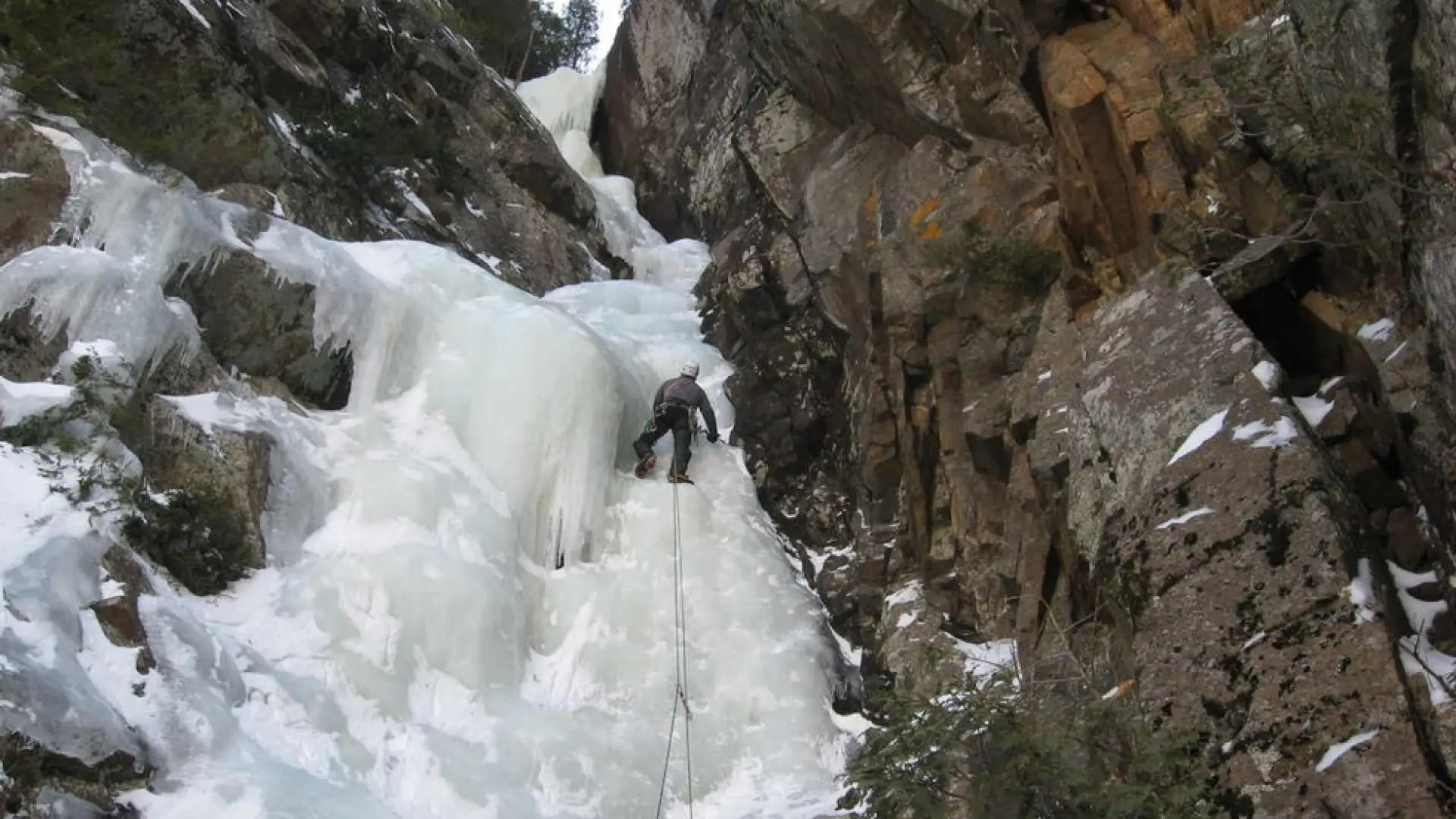 An ice climber going up a narrow flow