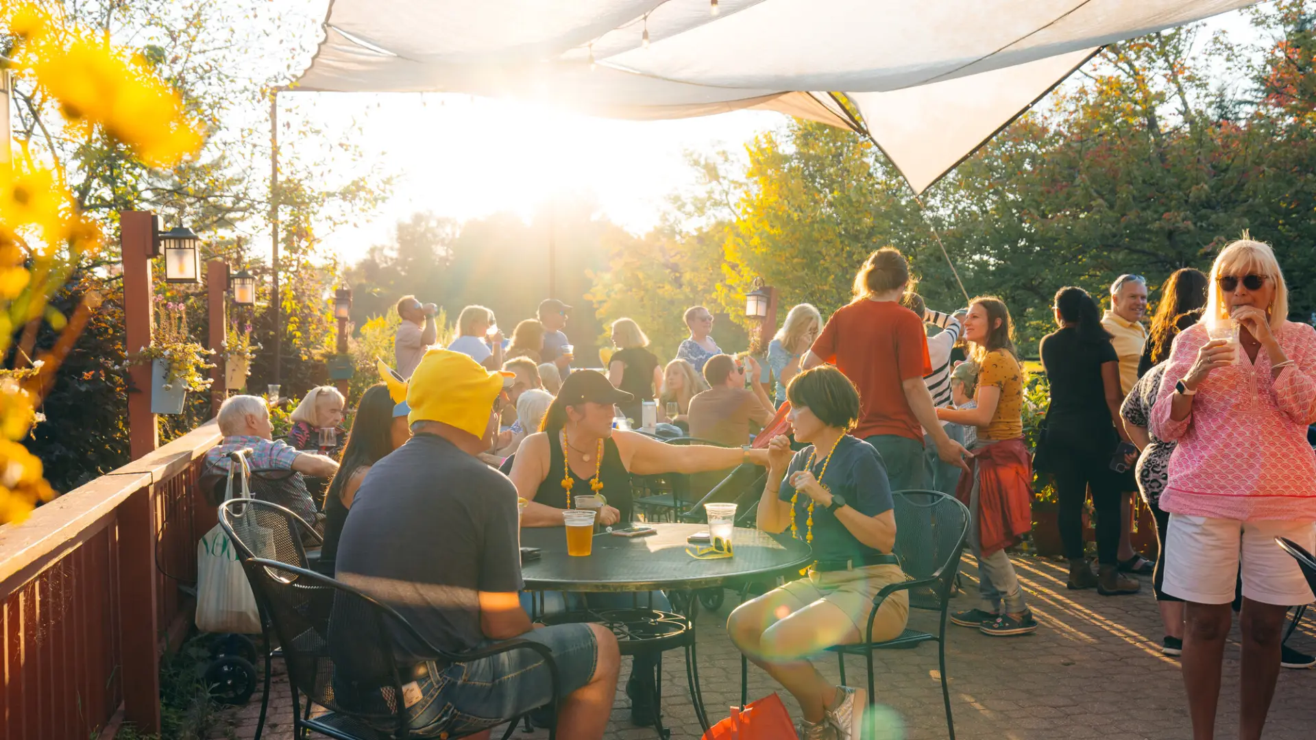 People seen on canopied outdoor patio sitting at tables and standing, some wearing duck accessories 