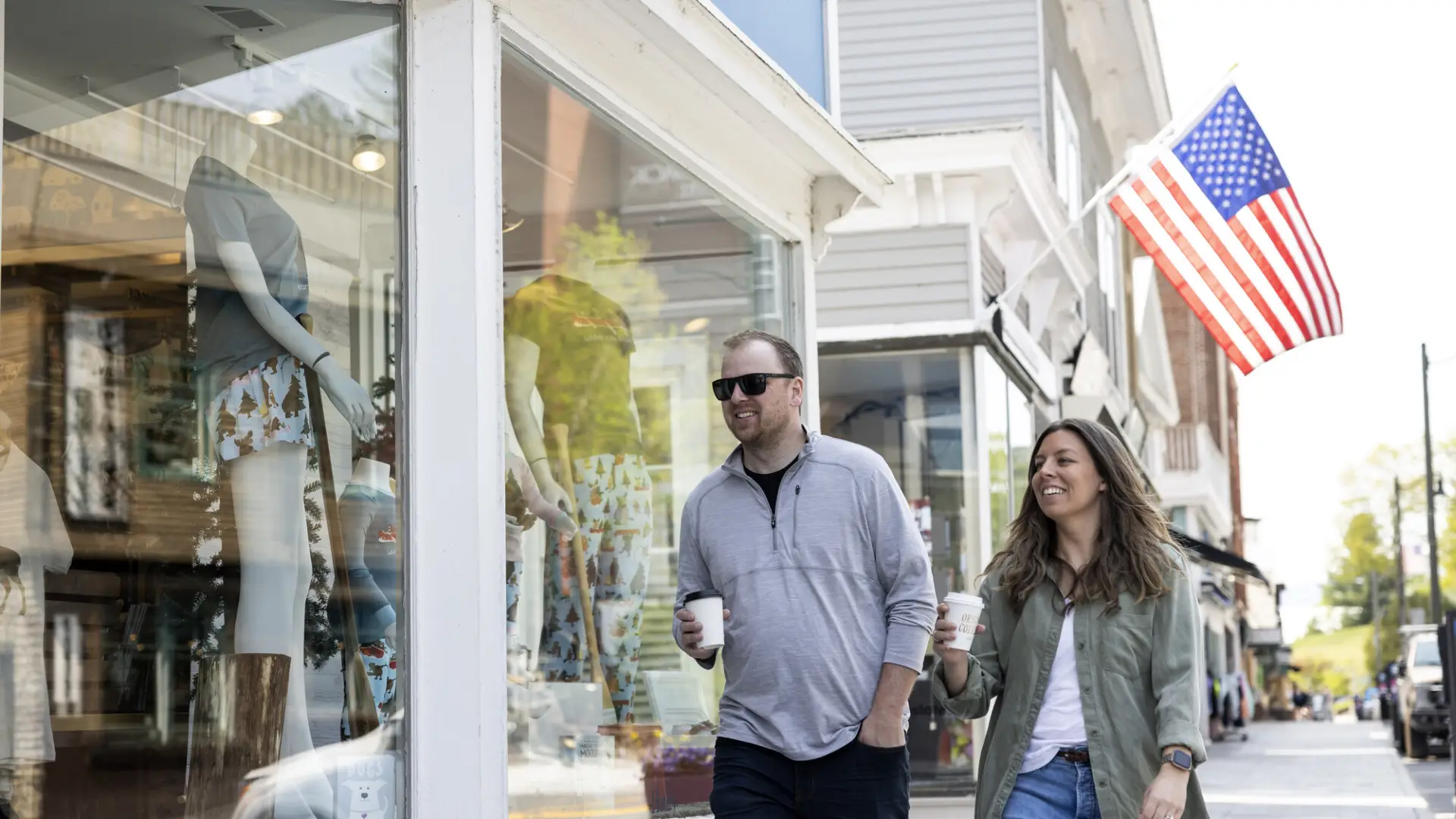 A man and woman wear spring-time outfits and window shop down Main Street.