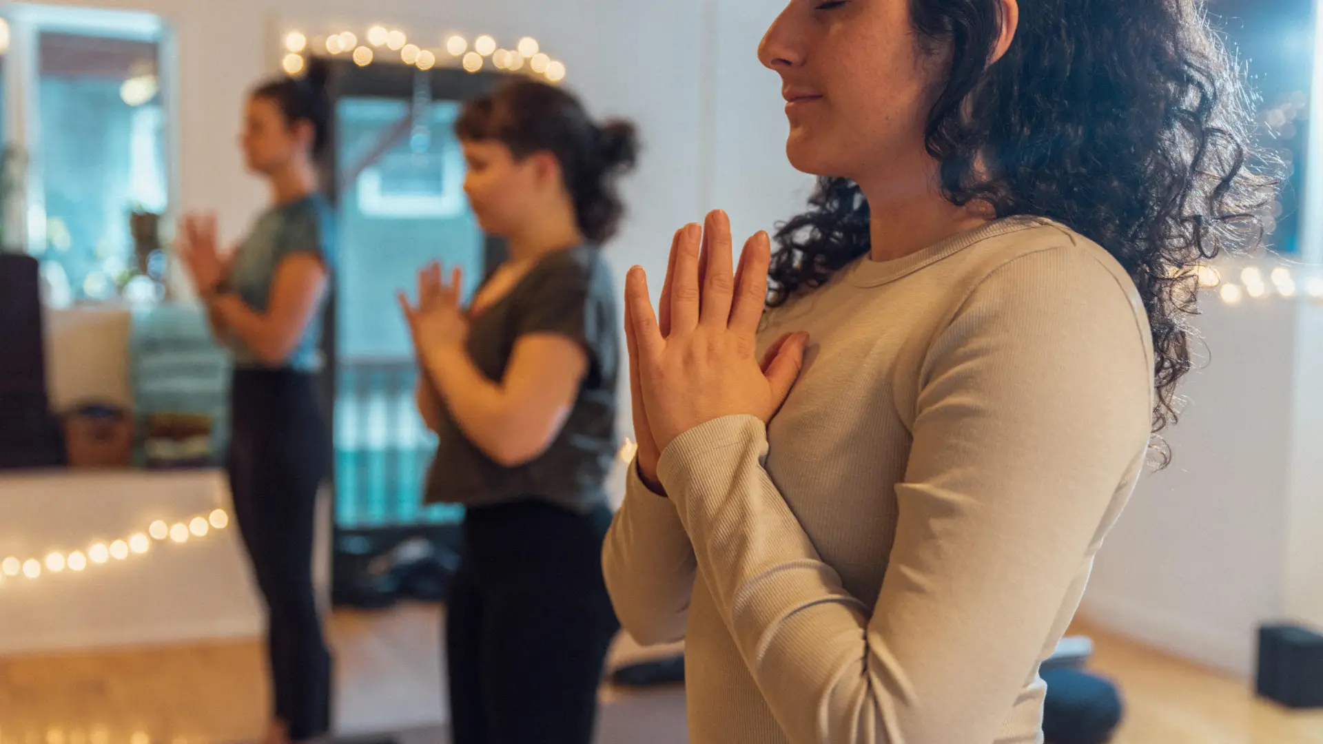 People prepare to begin their practice with their hands together in heart center.