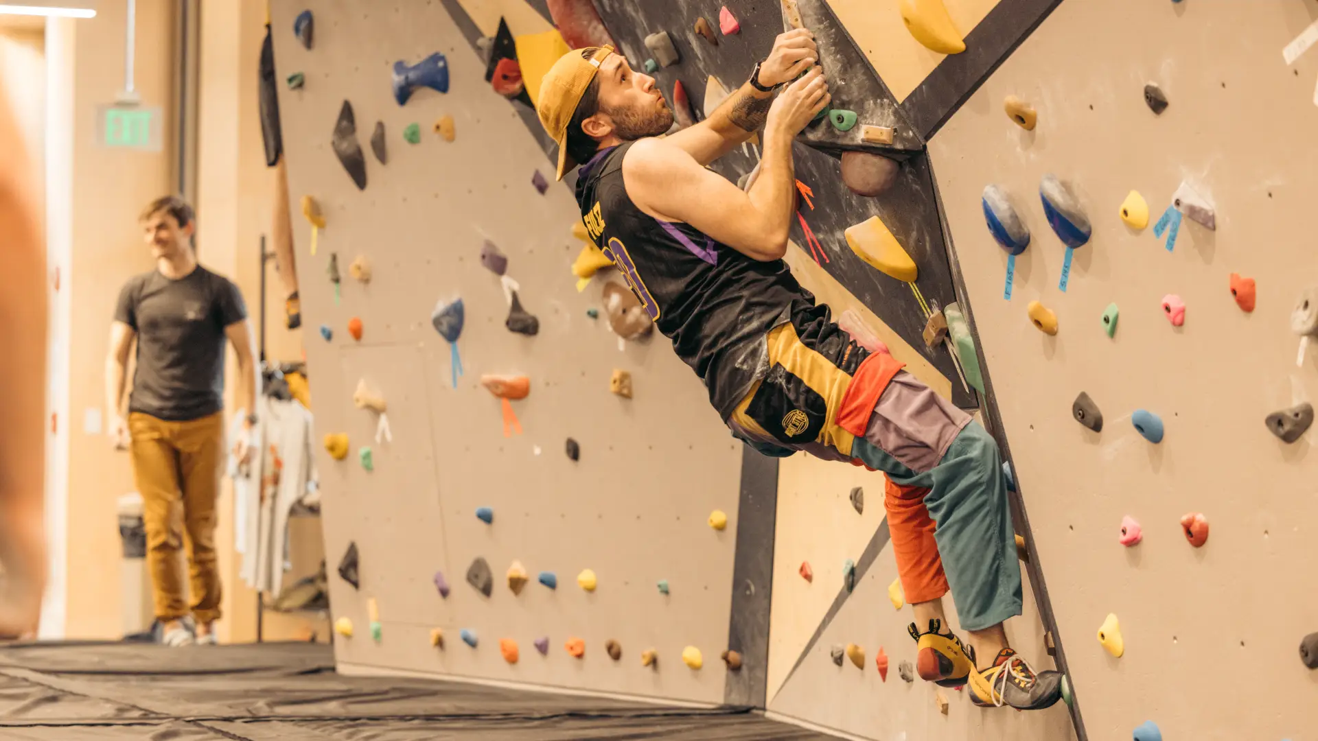 Climber holds onto climbing holds on an indoor bouldering wall just off the ground