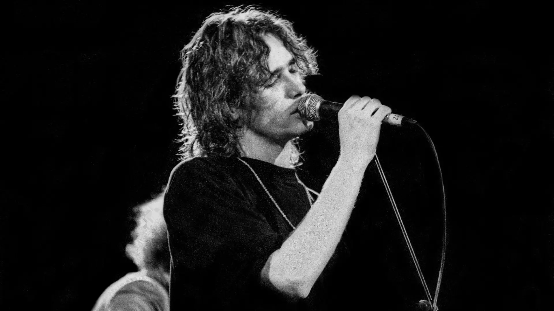 Black and white photo of Jeff Buckley singing into standing microphone