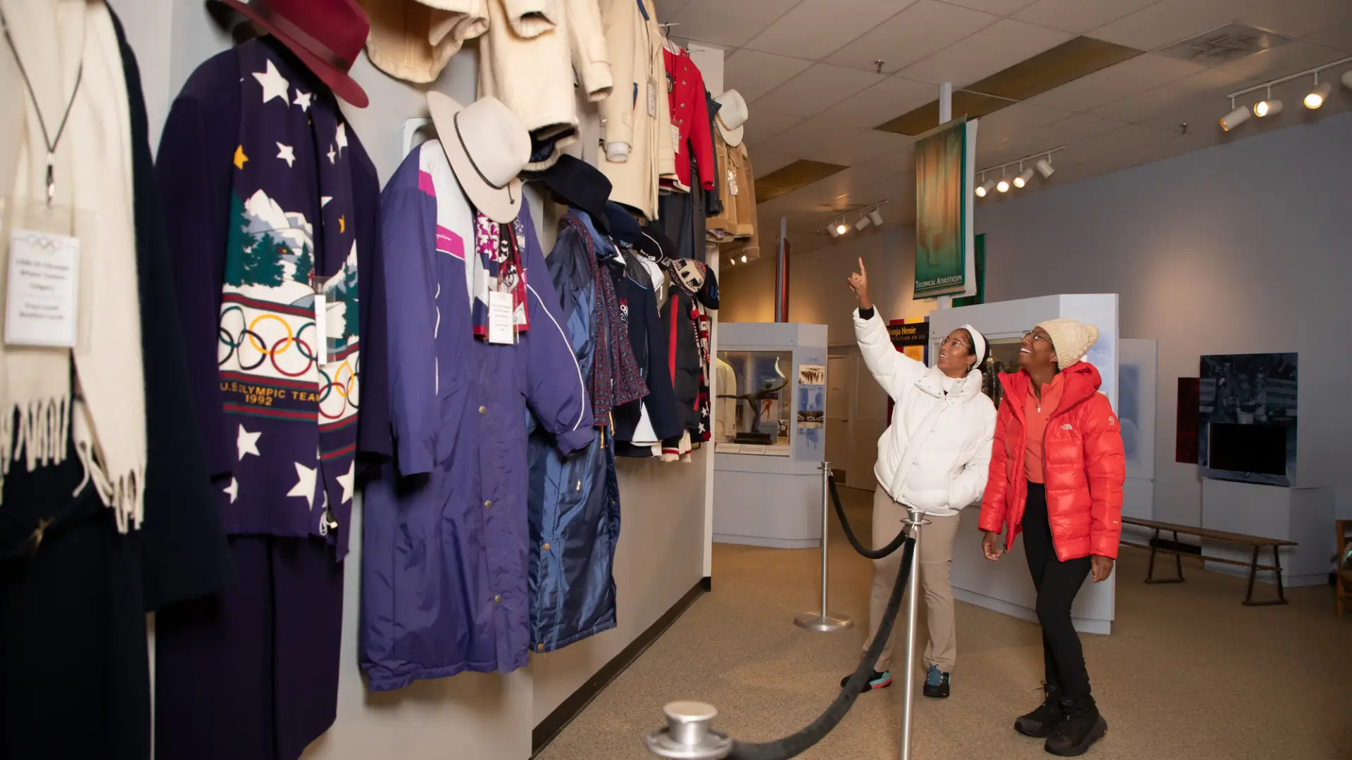Two women admire historic uniforms at the Lake Placid Olympic Museum.