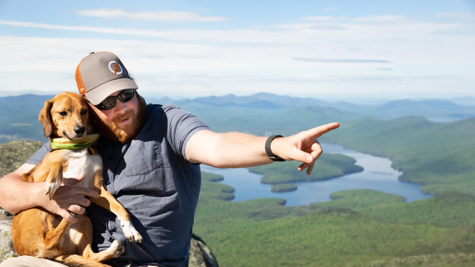 Man on the top of a mountain holding his dog