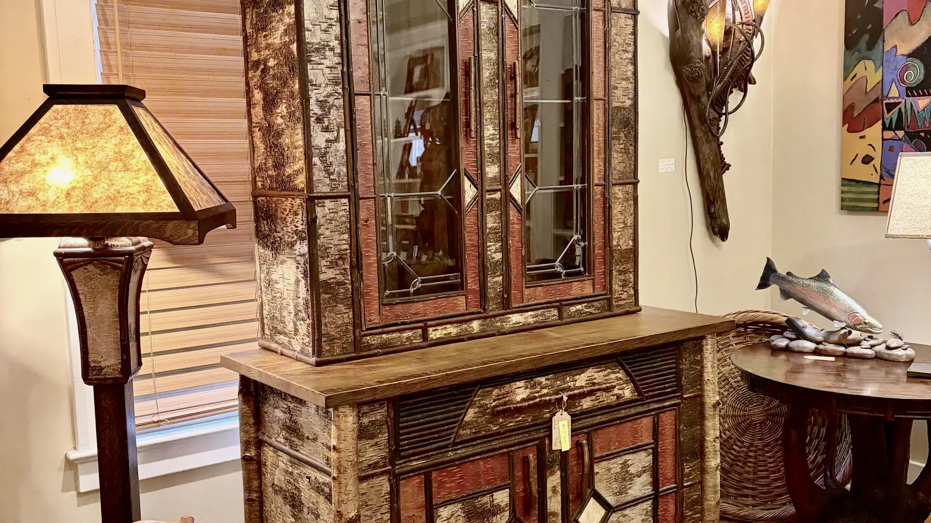 A birch bark decorated hutch with glass windows on the upper doors.