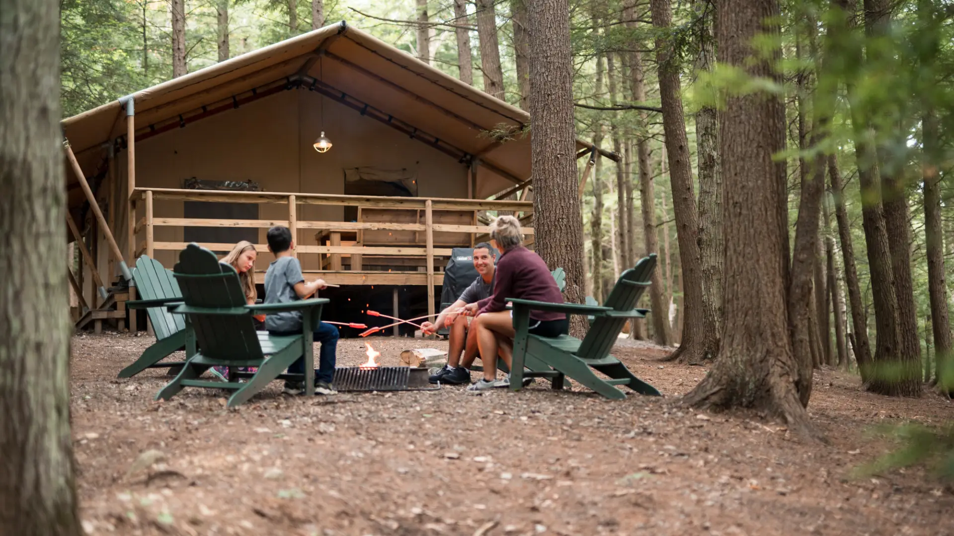 A family in front of a glamping cabin roasting marshmallows