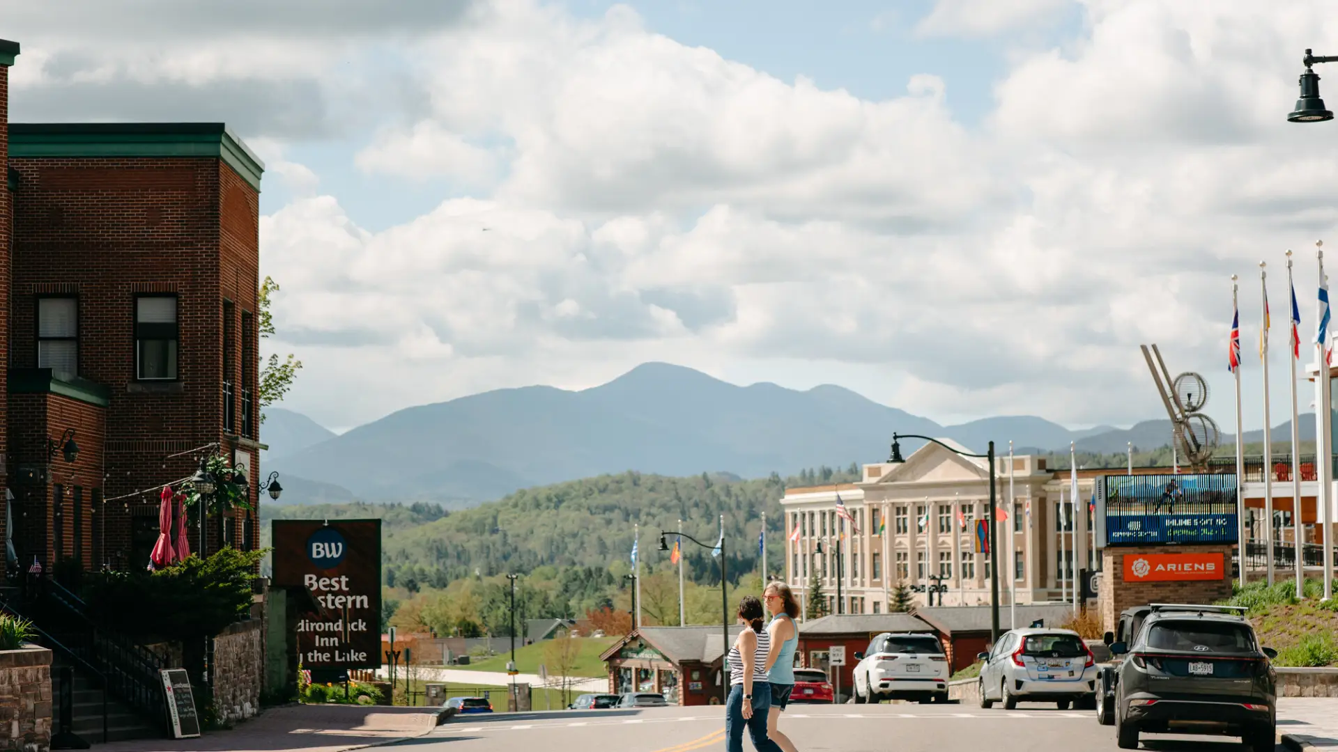 Two women walk across a main street.