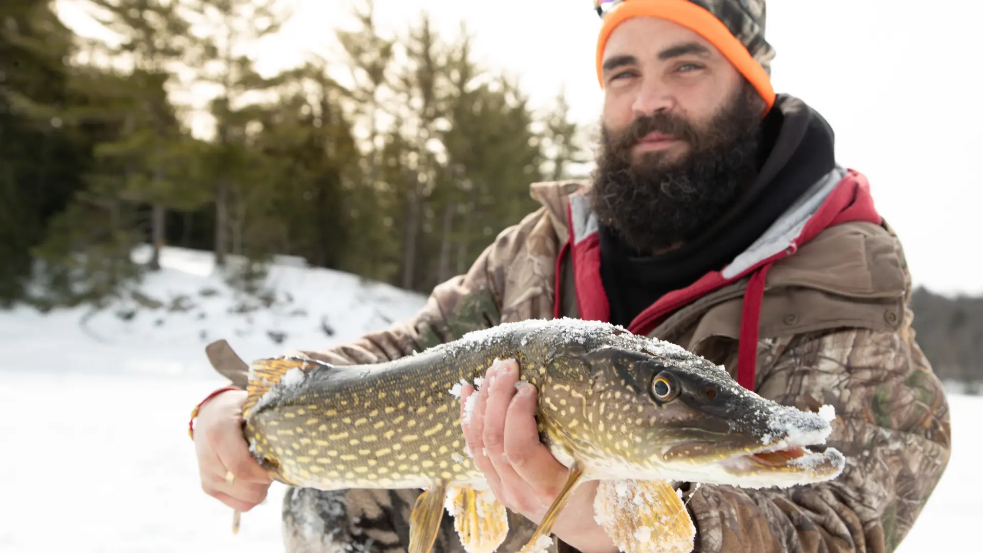 A man holds up a northern pike he caught ice fishing