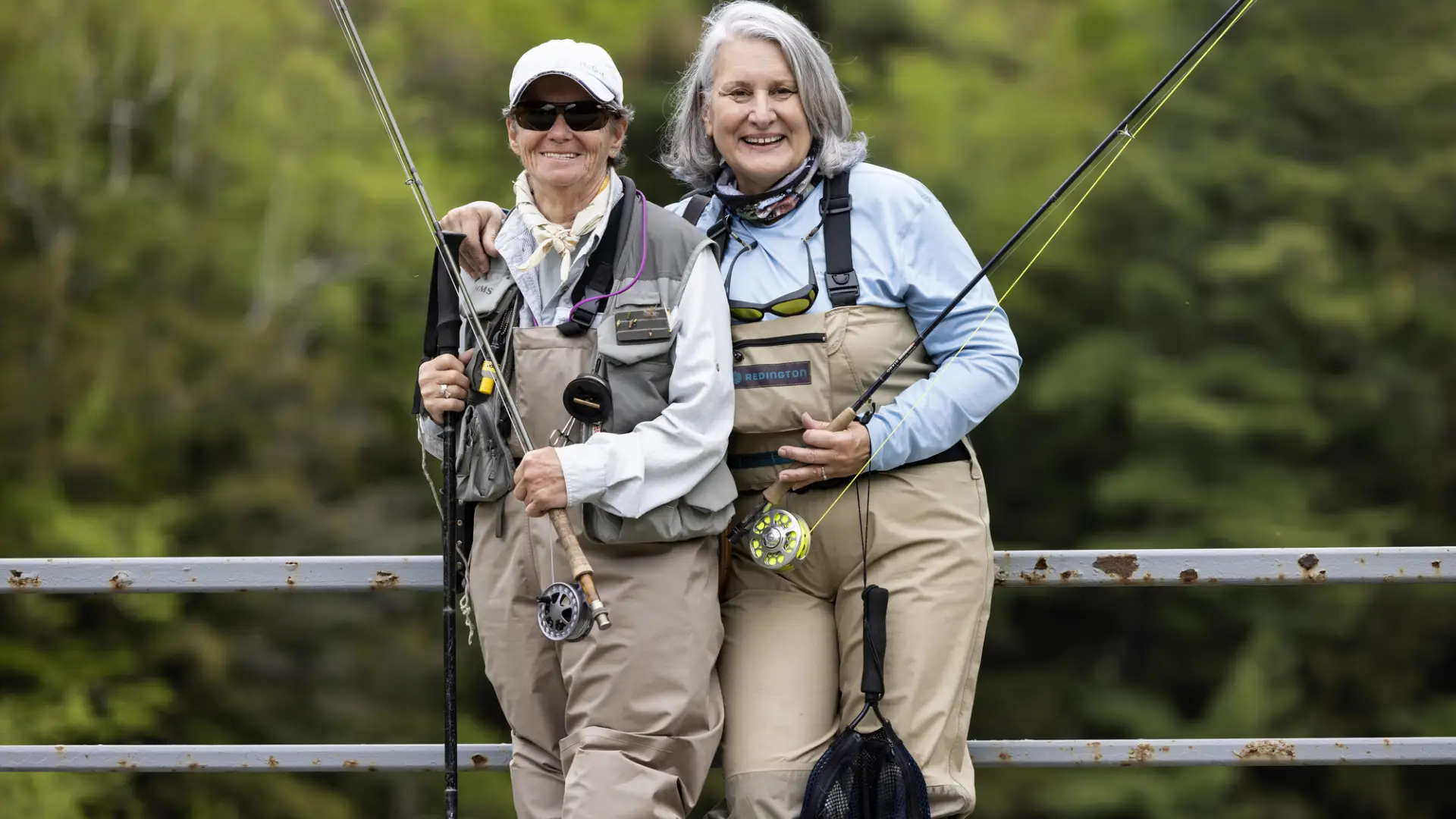 Two fisherwomen pose and smile holding poles
