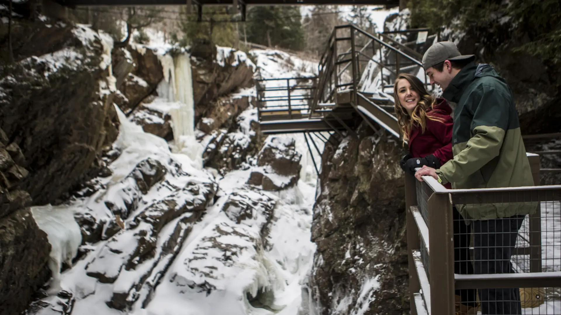 Two people at a frozen waterfall, overlooking from a boardwalk