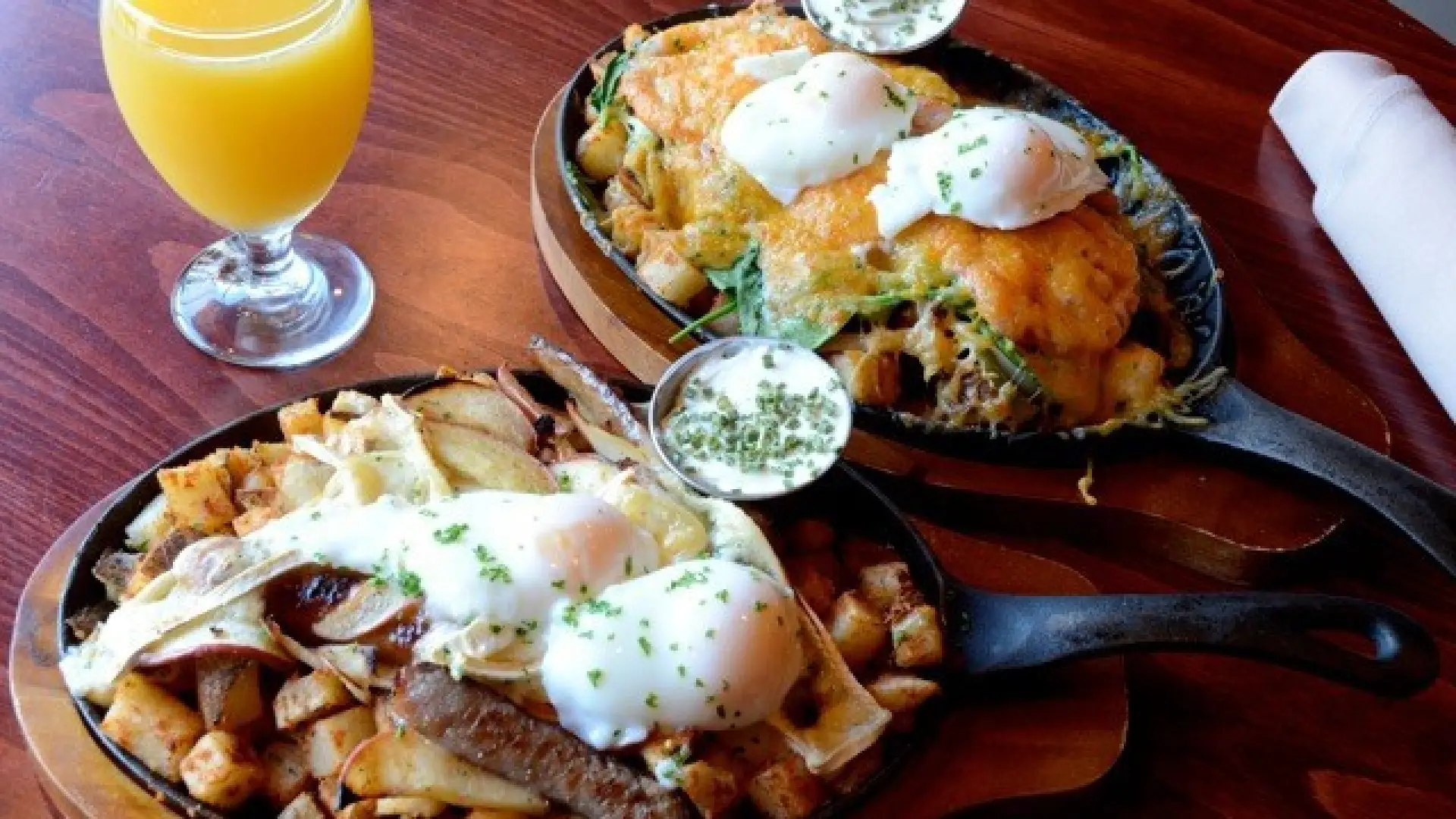 Two breakfast skillets served with orange juice.