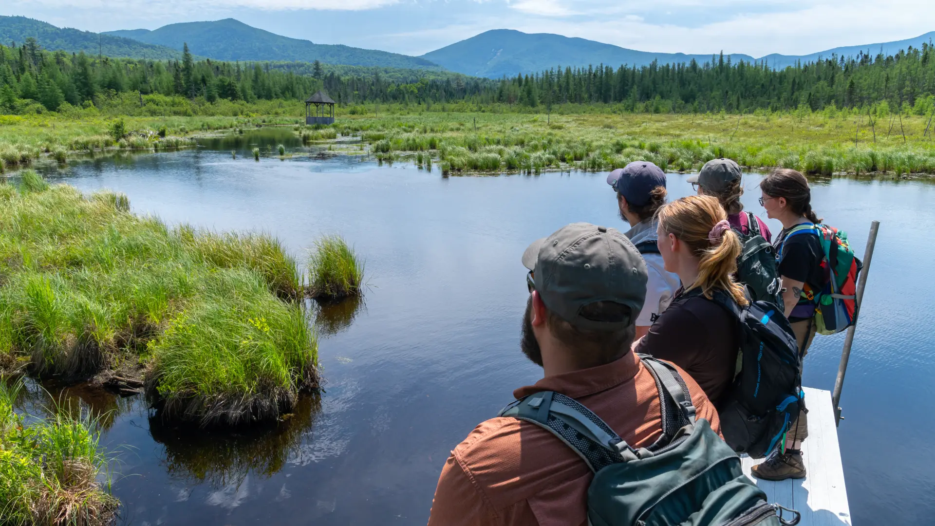 A group of people standing on a wooden walkway on the water