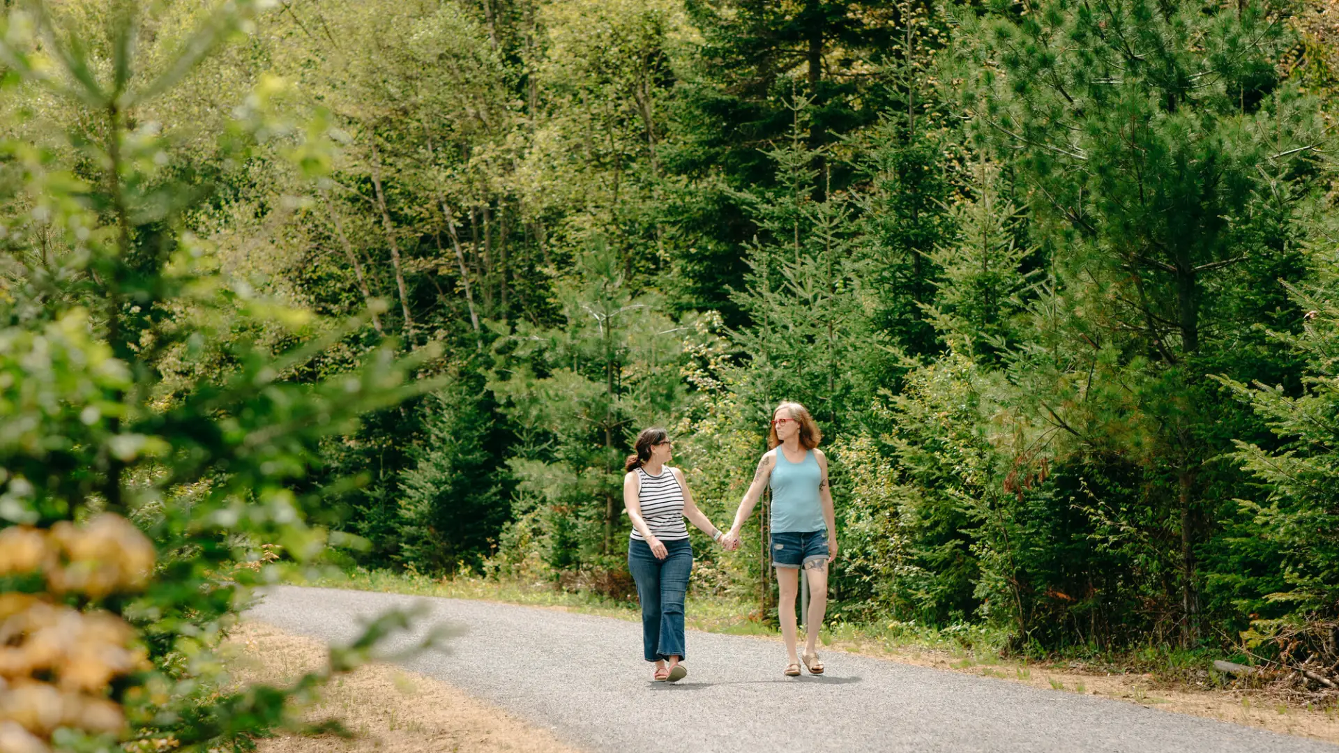 Two women in summer clothing walk on Adirondack Rail Trail