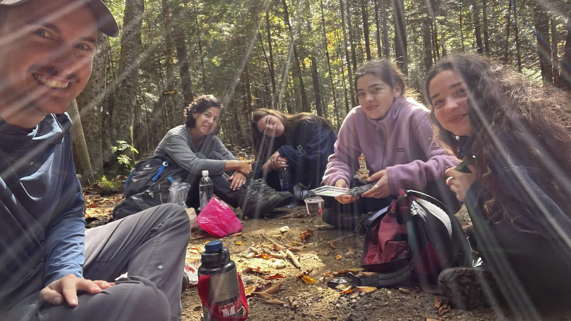 A group sits for a break with sunbeams shining through the trees