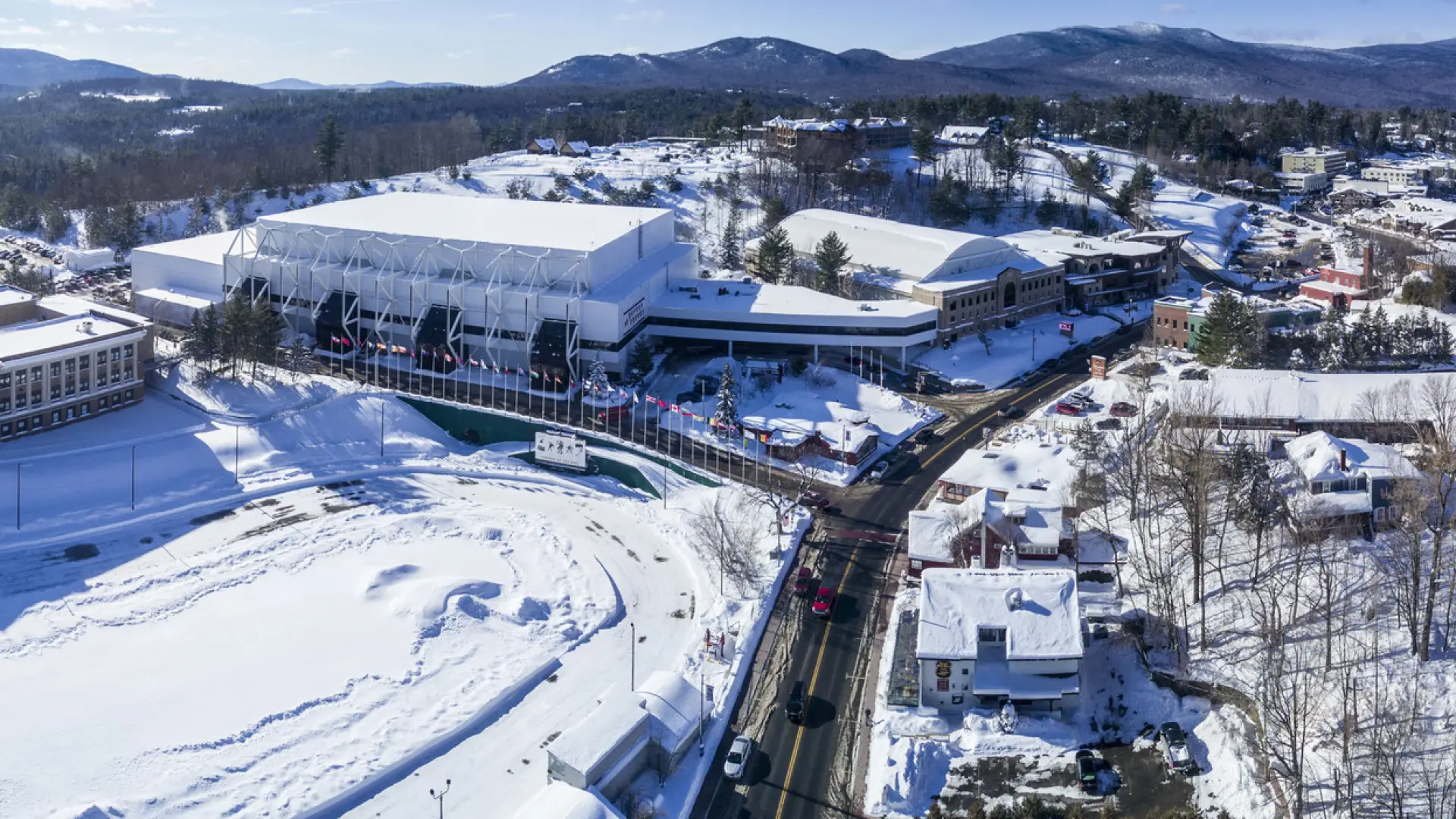 An aerial view of a white building covered in snow sitting at the end of a street. 