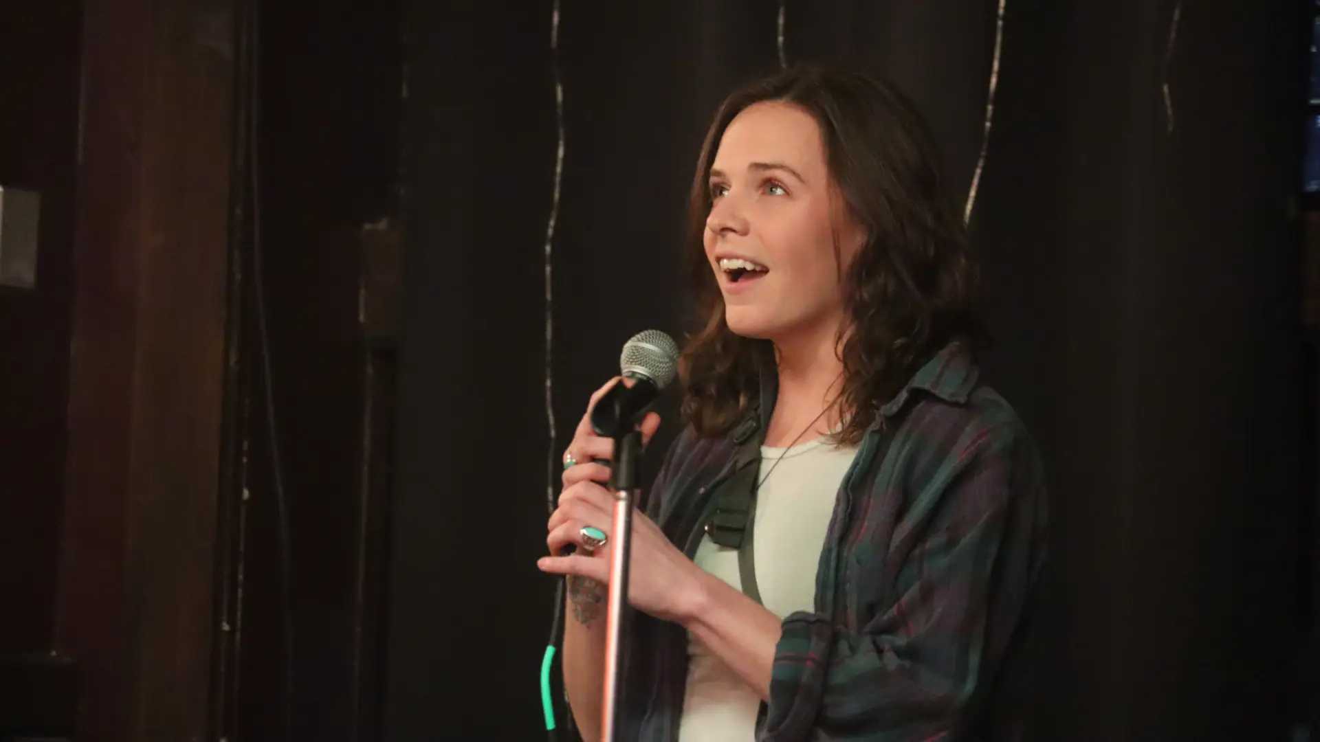 woman stands on stage talking into microphone
