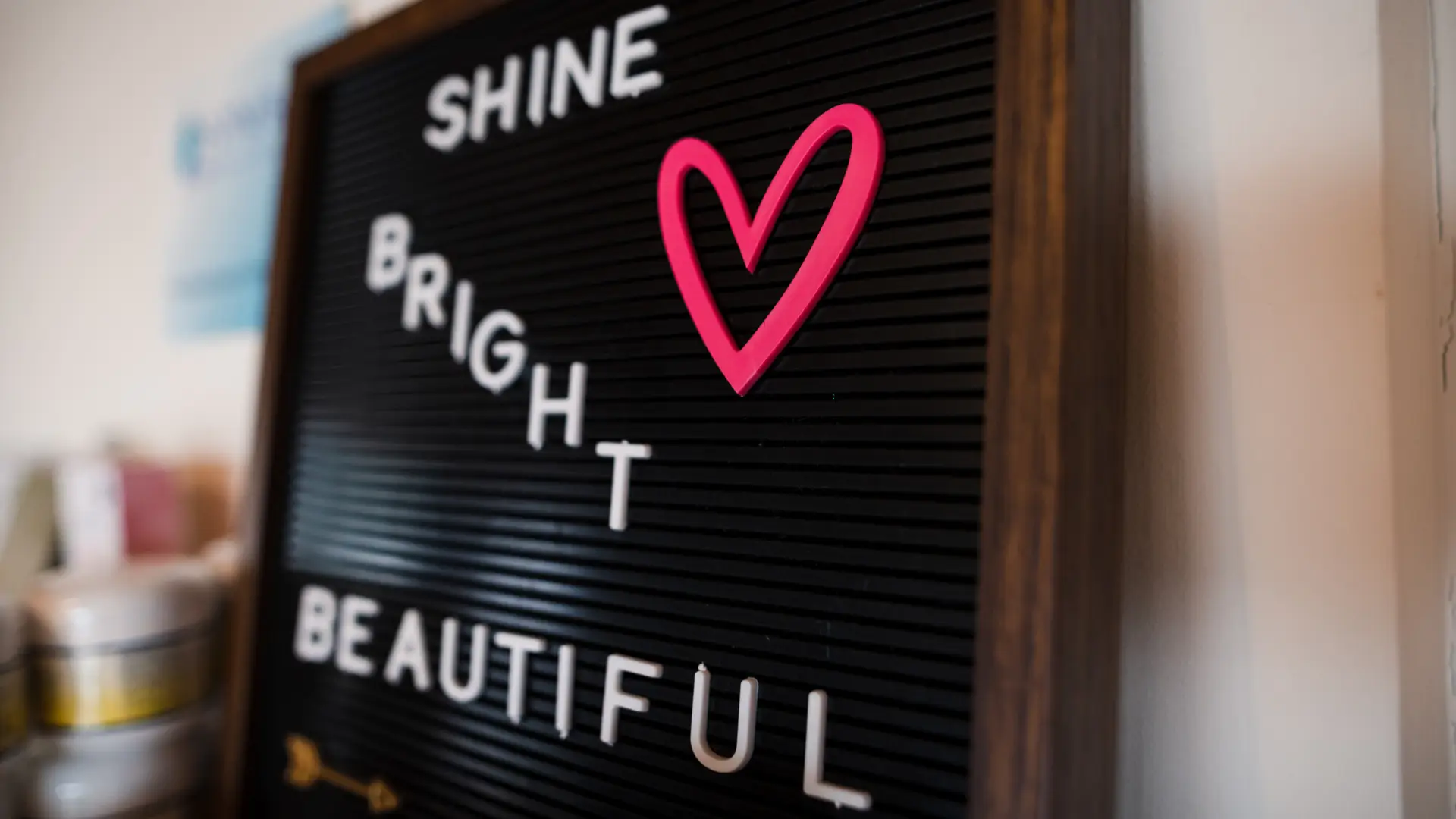 Black board sign with "Shine Bright Beautiful" in white lettering and a pink heart