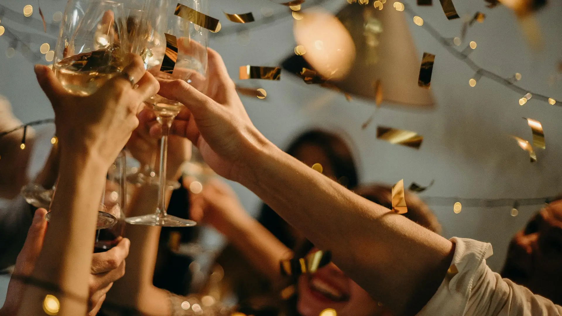 Stock image of hands raising champagne flutes among confetti