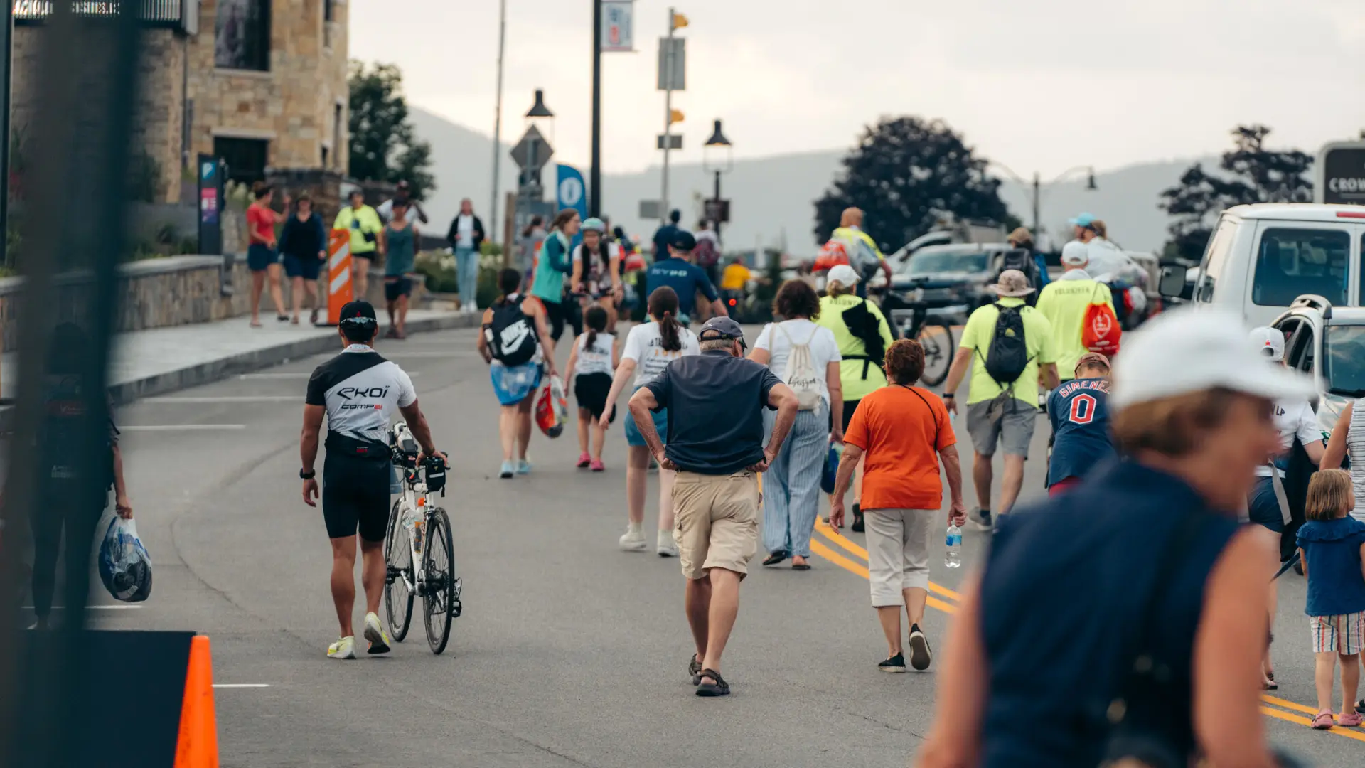 Athletes and spectators walk on road in Lake Placid during Ironman