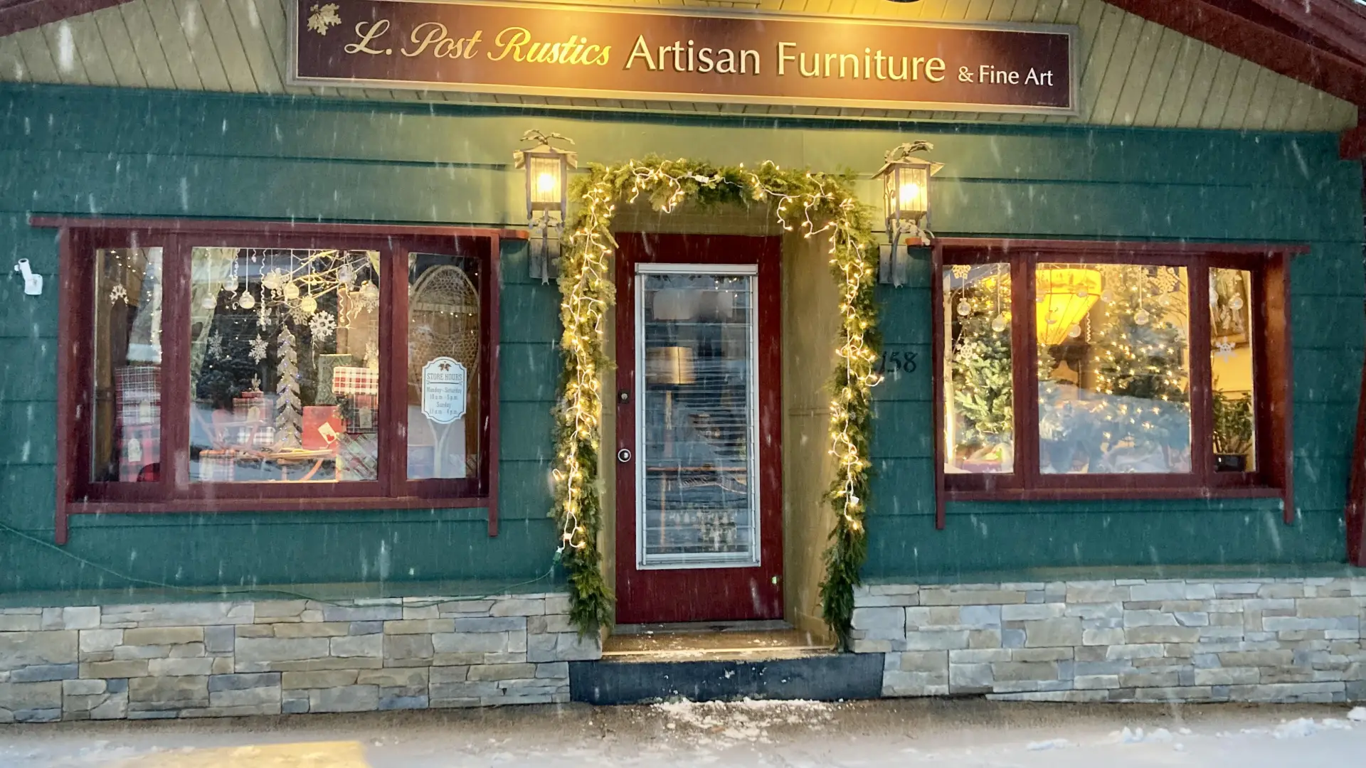 A gentle snow falls out front of the entry to L Post Rustics Artisan Furniture & Fine Art.
