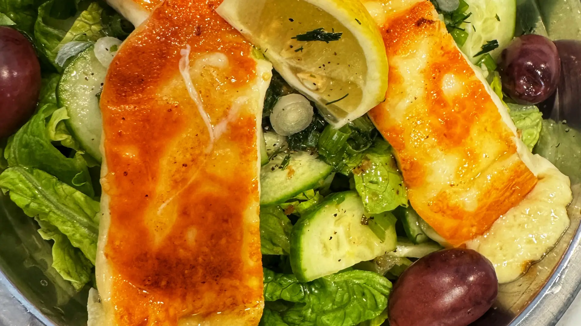 Greek salad topped with Halloumi with lemon