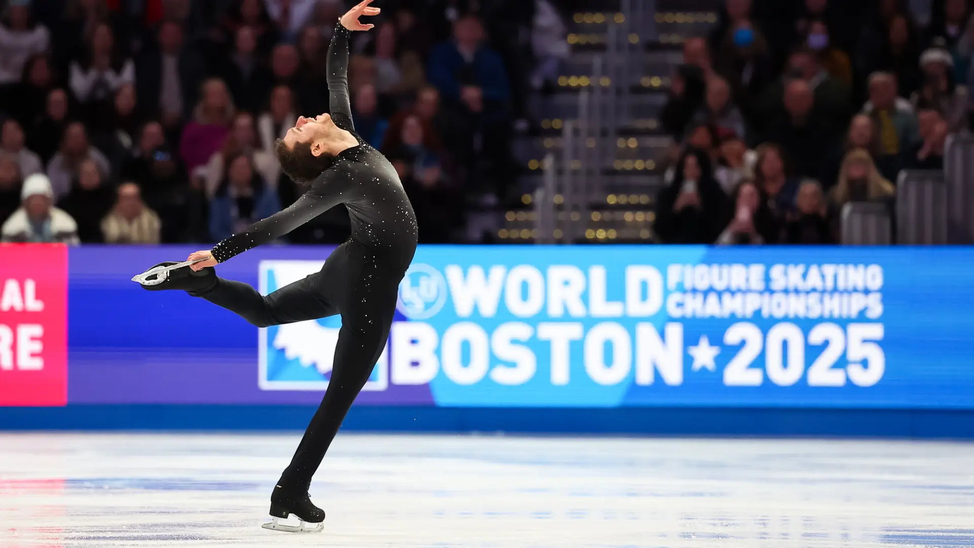 Male figure skater in black long sleeve and long pant spandex costume performs back bending move on ice