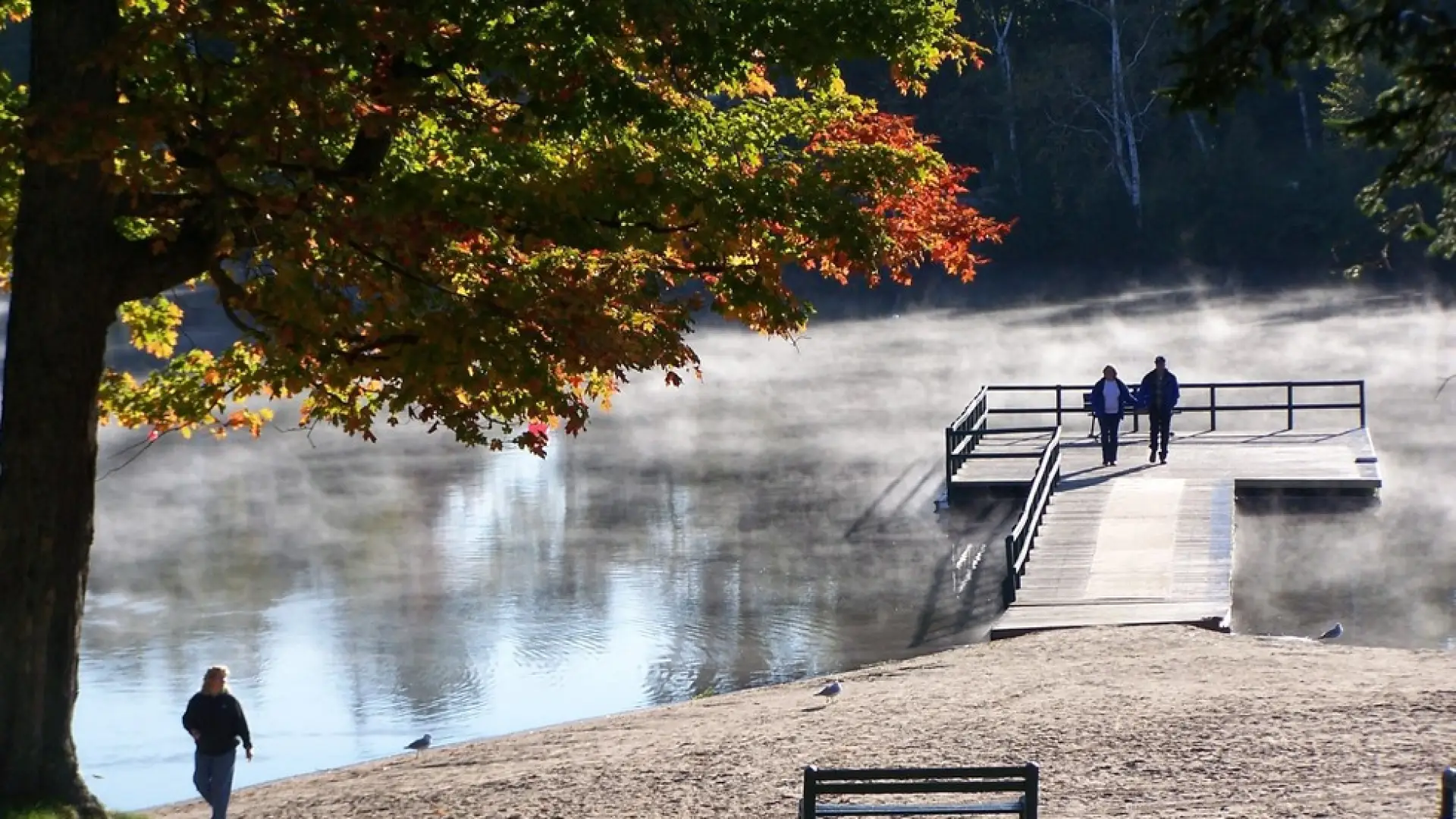 Some people on a dock with mist rising from the water