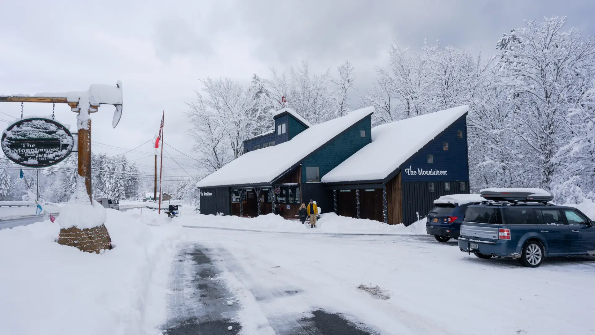 A few people walk into a snow-covered gear shop