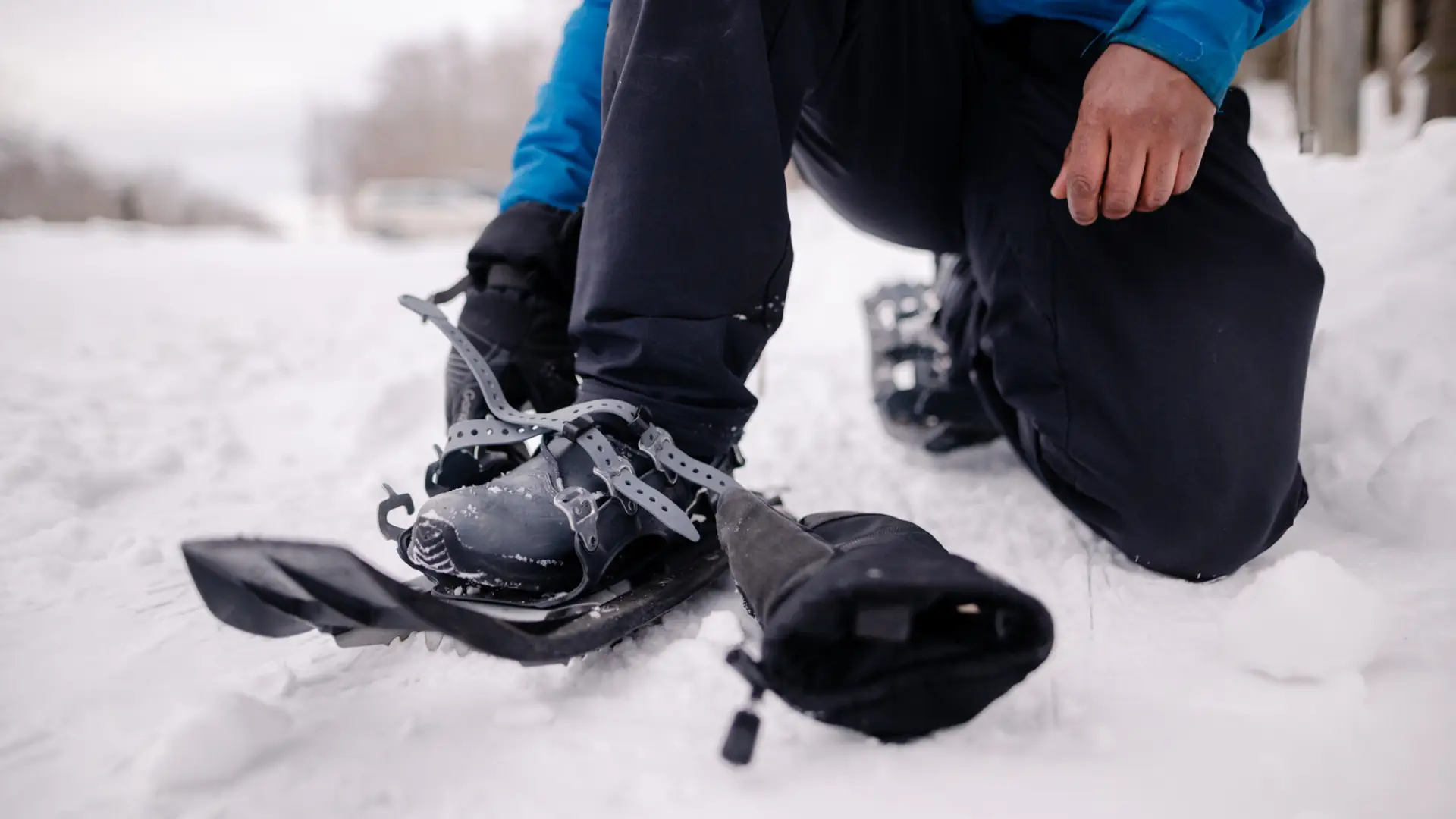 A person strapping on snowshoes