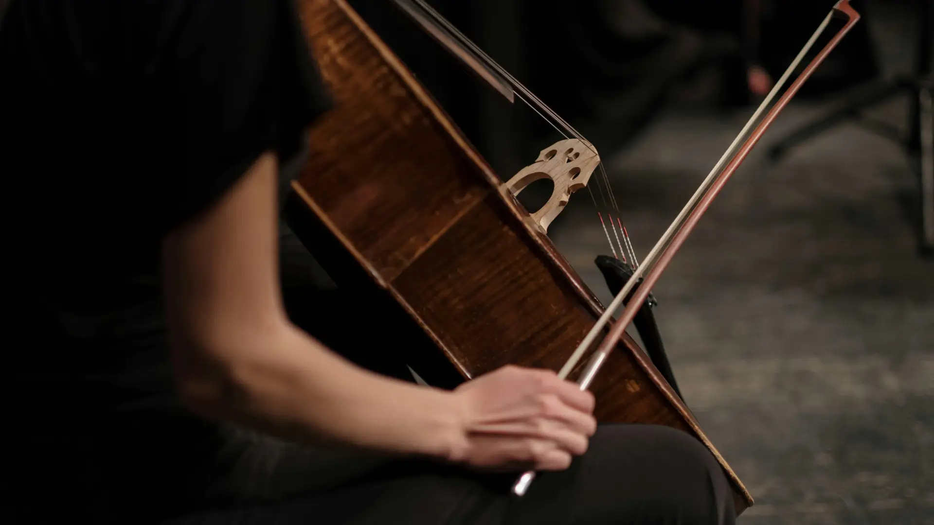 Stock image of woman in black dress sitting with cello holding bow