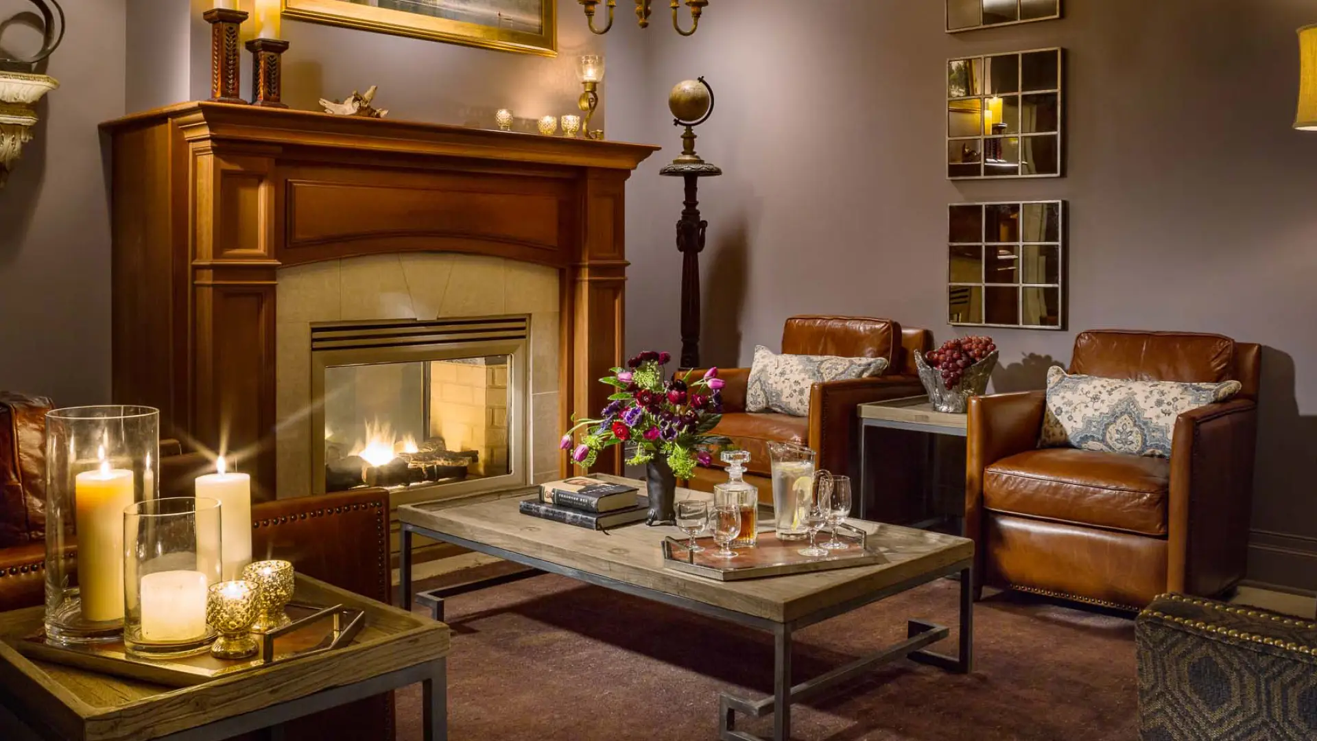 The cozy men's lounge with deep and dark leather chairs, candles, fireplace and warm ambiance