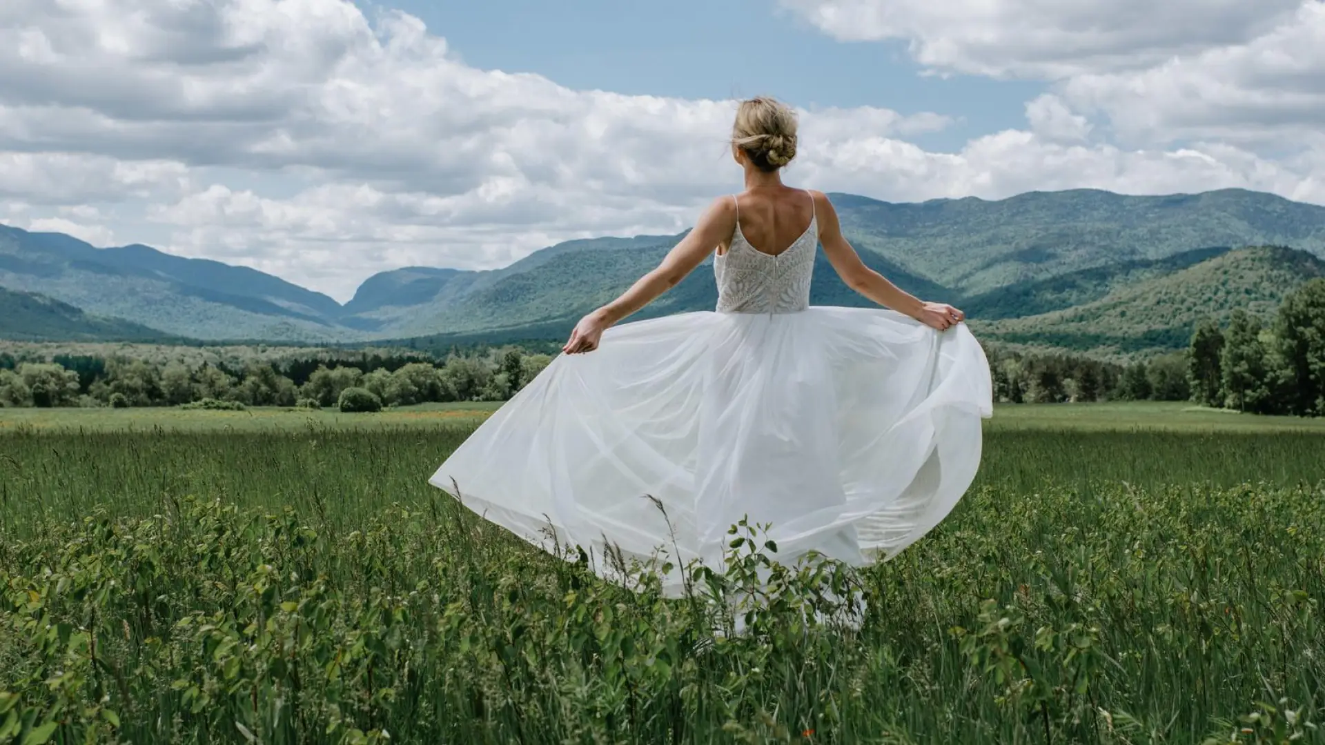 A bride fans out her dress and takes in the majestic view of the high peaks