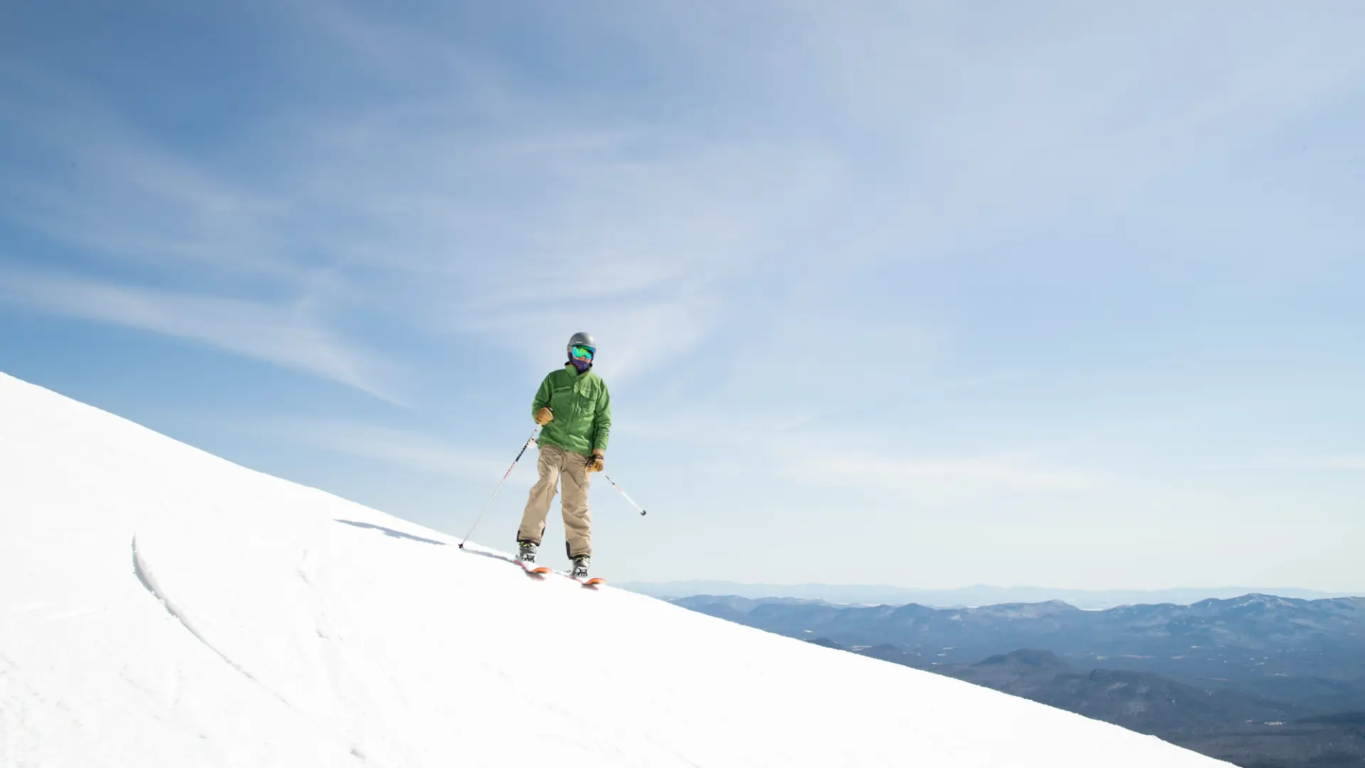 A skier standing on the side of a snowy mountain.