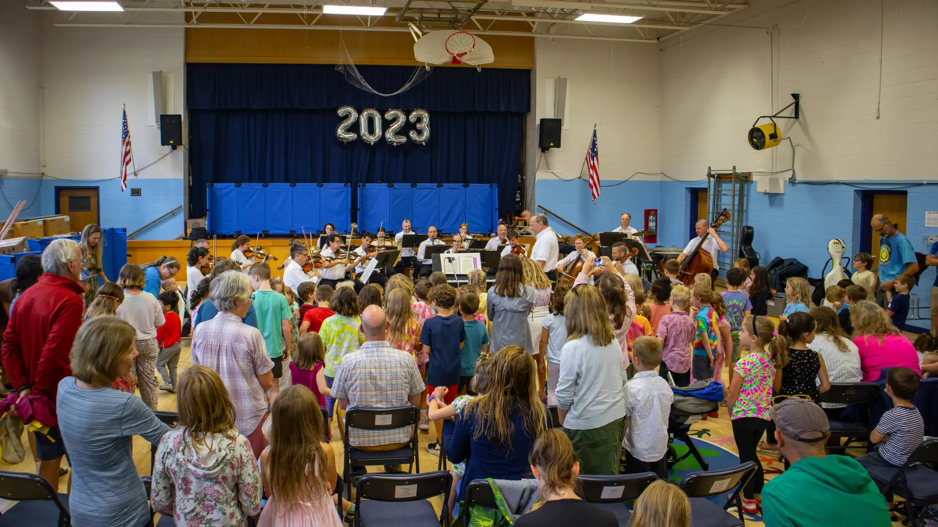 A full gymnasium of adults and kids waiting to enjoy the classical music of the Lake Placid Sinfonietta