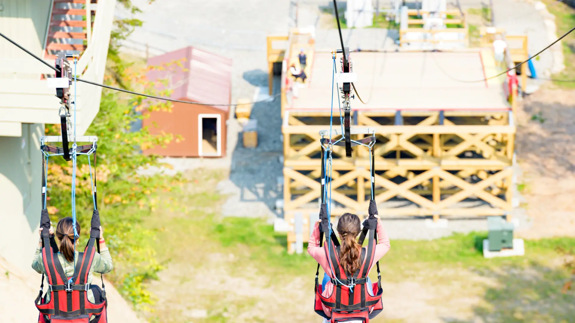 two women ride a zipline down to a platform.