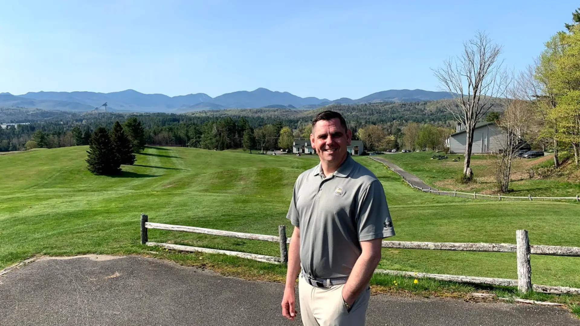 Lake Placid Club golf pro Jim Beauregard poses with the course and its Adirondack views behind him.
