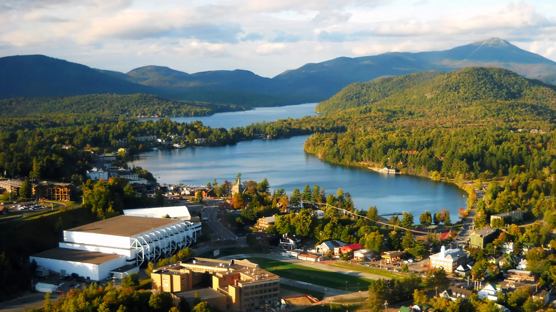 An aerial view of a town on a lake with wilderness around it.